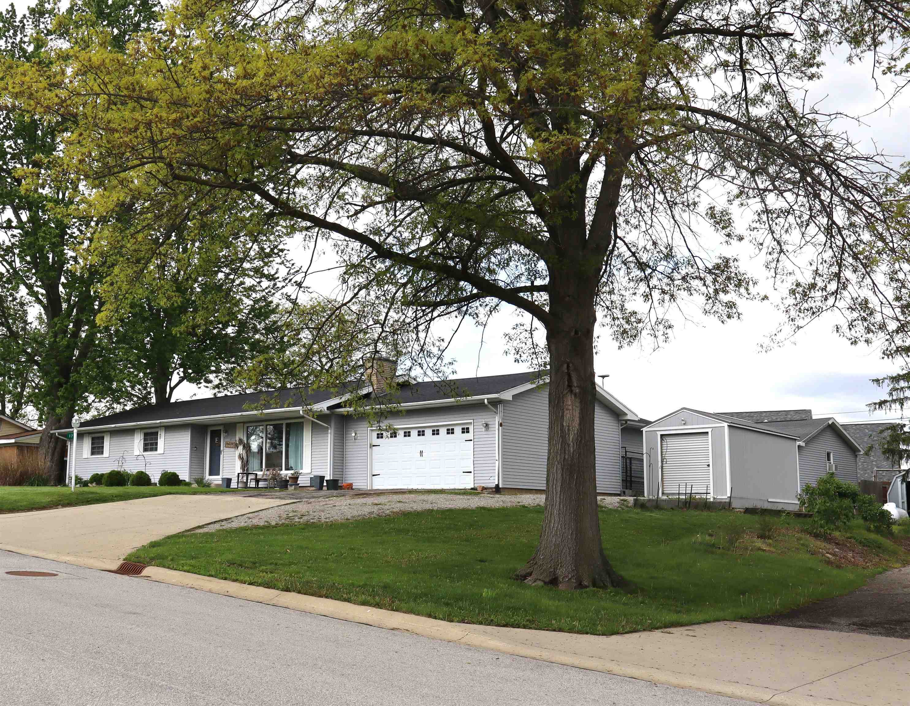Ranch-style residence featuring light gray siding and a black shingle roof