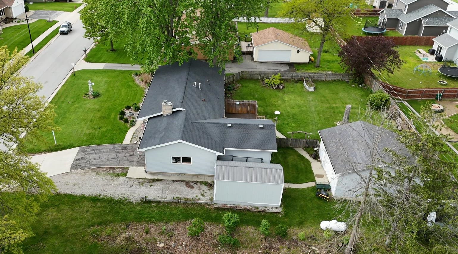 Aerial perspective showcasing a light blue residence with a dark shingle roof