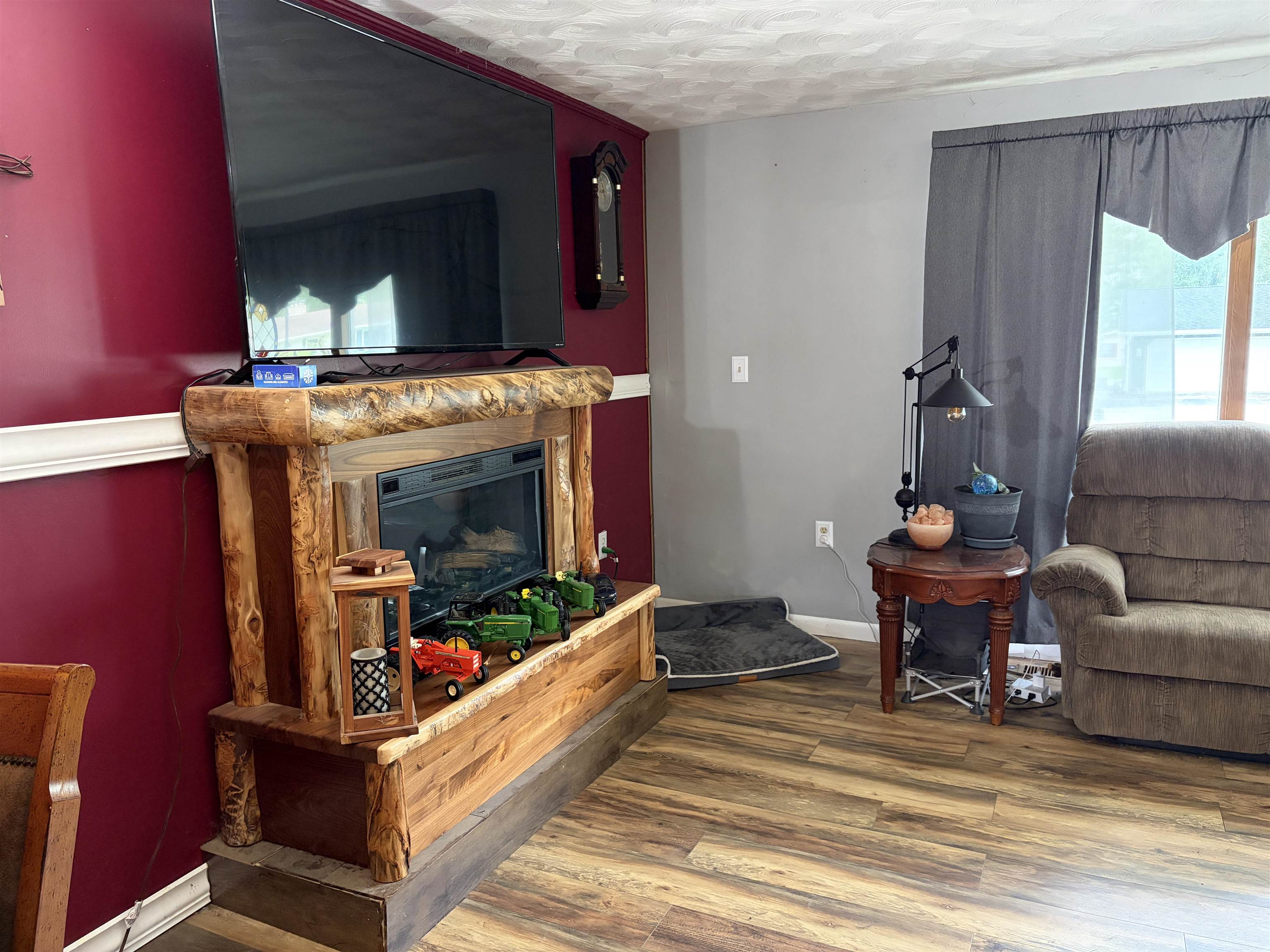 Living area featuring wood-finish flooring, a built-in fireplace with a rustic wood surround, and two-tone wall paint