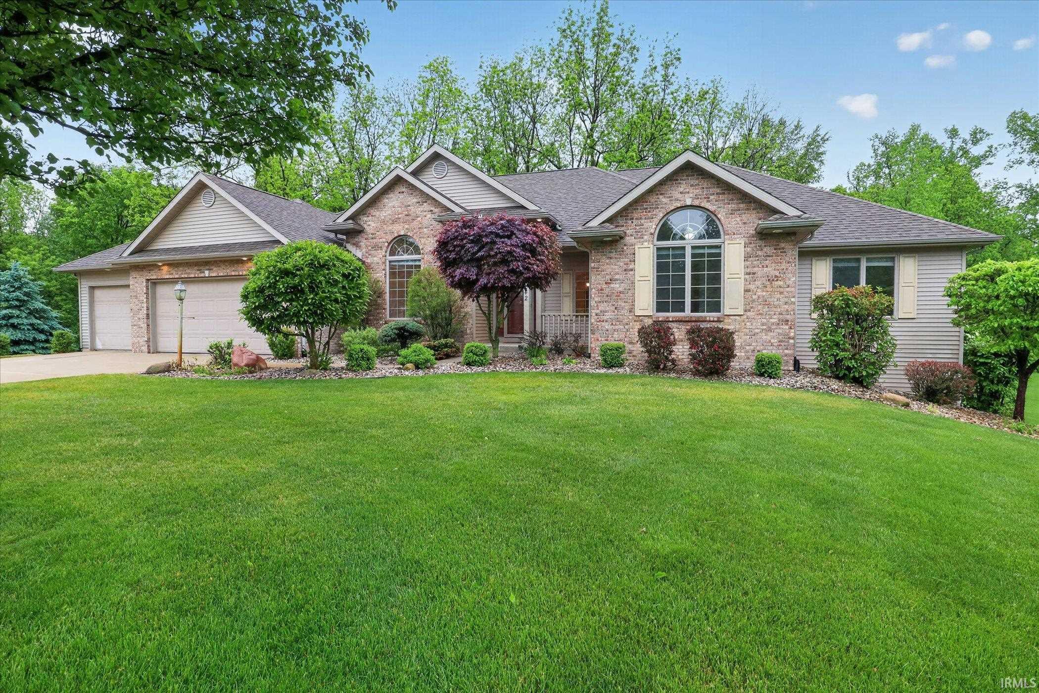 Ranch-style exterior featuring brick and siding finishes, an arched transom window, and a two-car garage