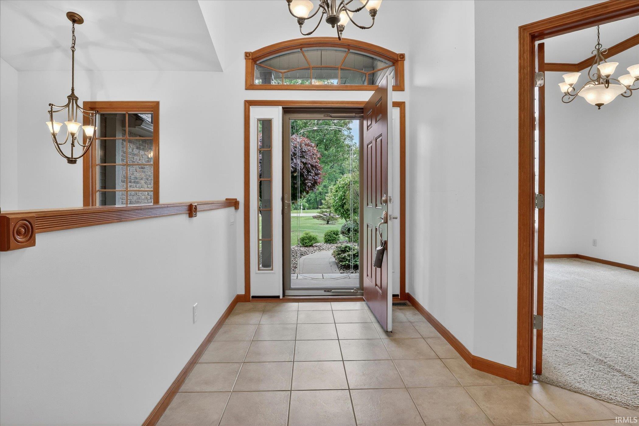 Foyer featuring tile flooring, a wood-trimmed entryway, and a decorative arched transom window