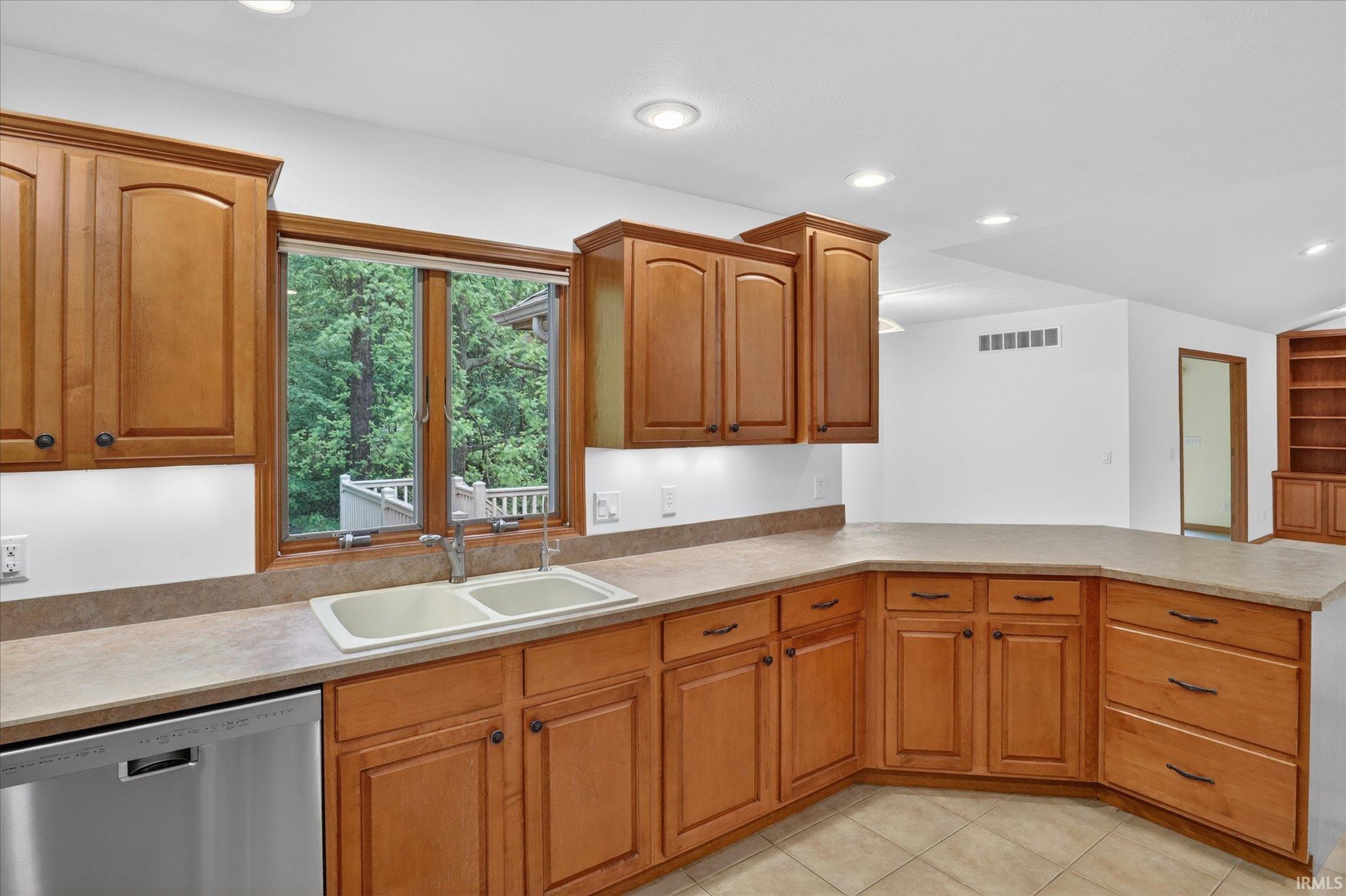 Kitchen featuring light wood cabinetry, a double basin sink, and a stainless steel dishwasher