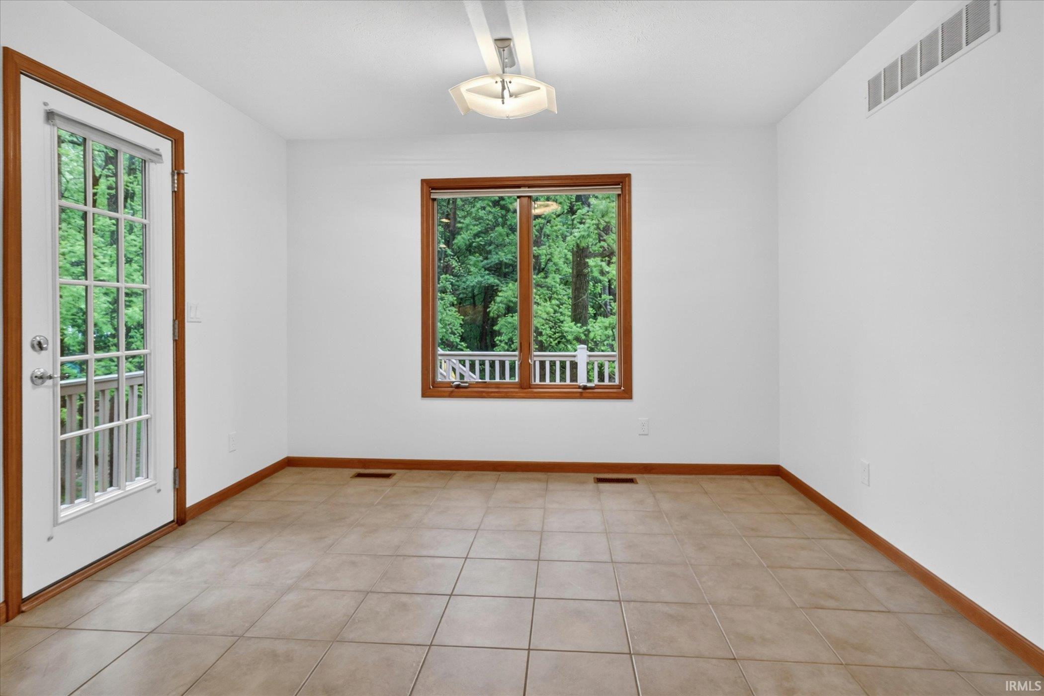 Spacious room featuring tile flooring, white walls, and a wood-framed window