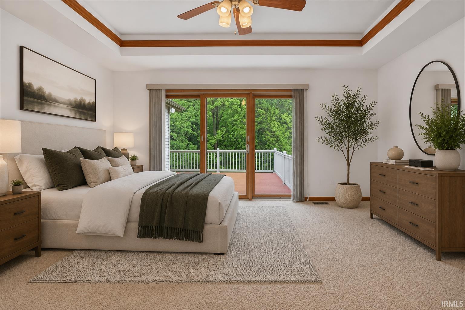 Spacious bedroom featuring a tray ceiling with wood beam accents and a ceiling fan