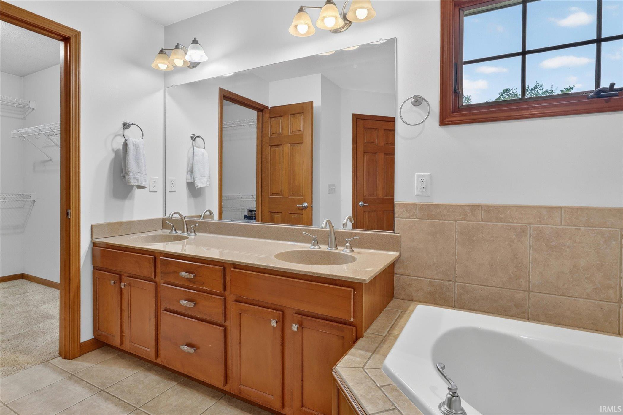 Bathroom vanity featuring dual undermount sinks, a light-toned countertop, and wood cabinetry