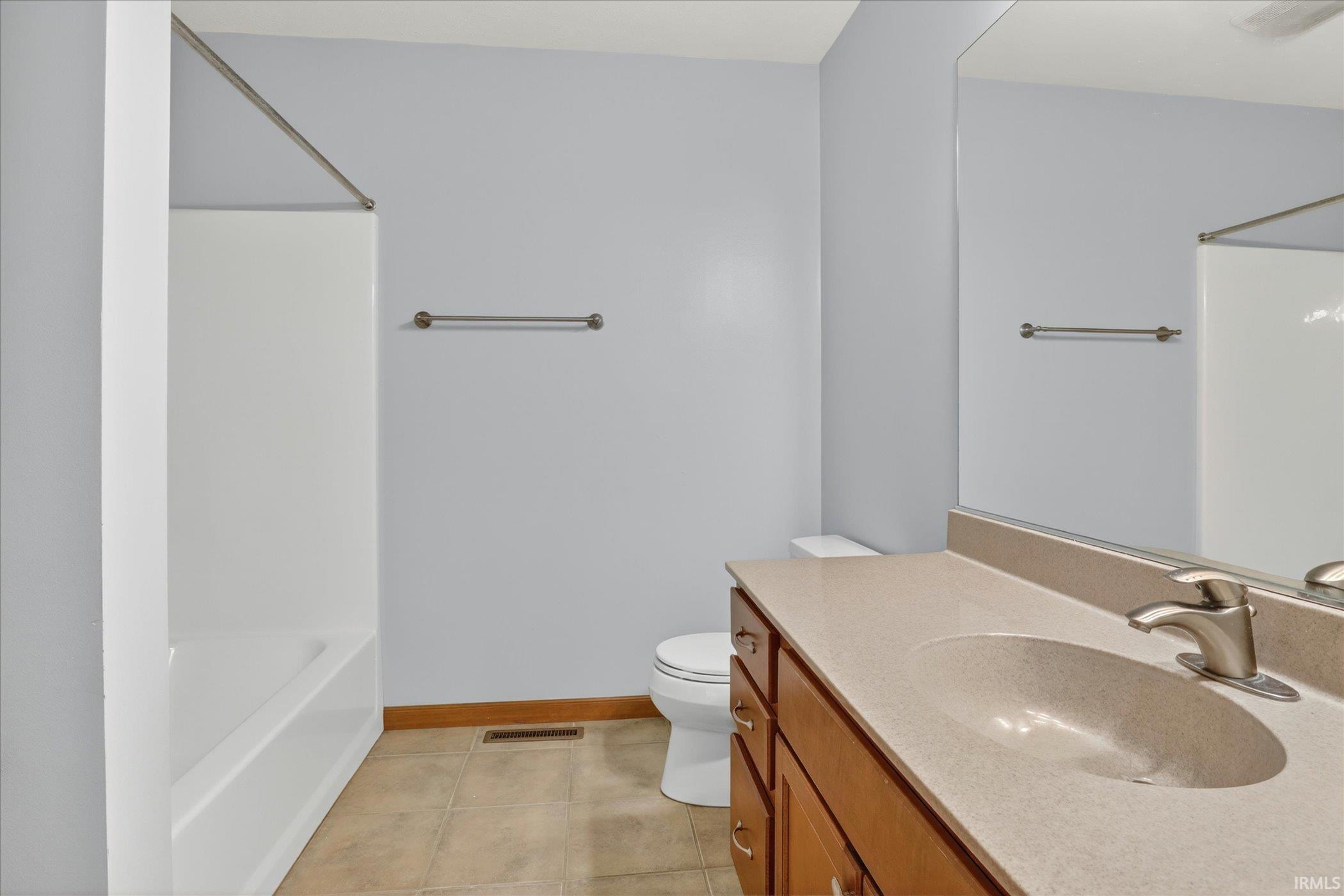 Bathroom featuring a single vanity with an integrated sink and brushed nickel faucet, a full-width mirror, tile flooring, and a shower/tub combination