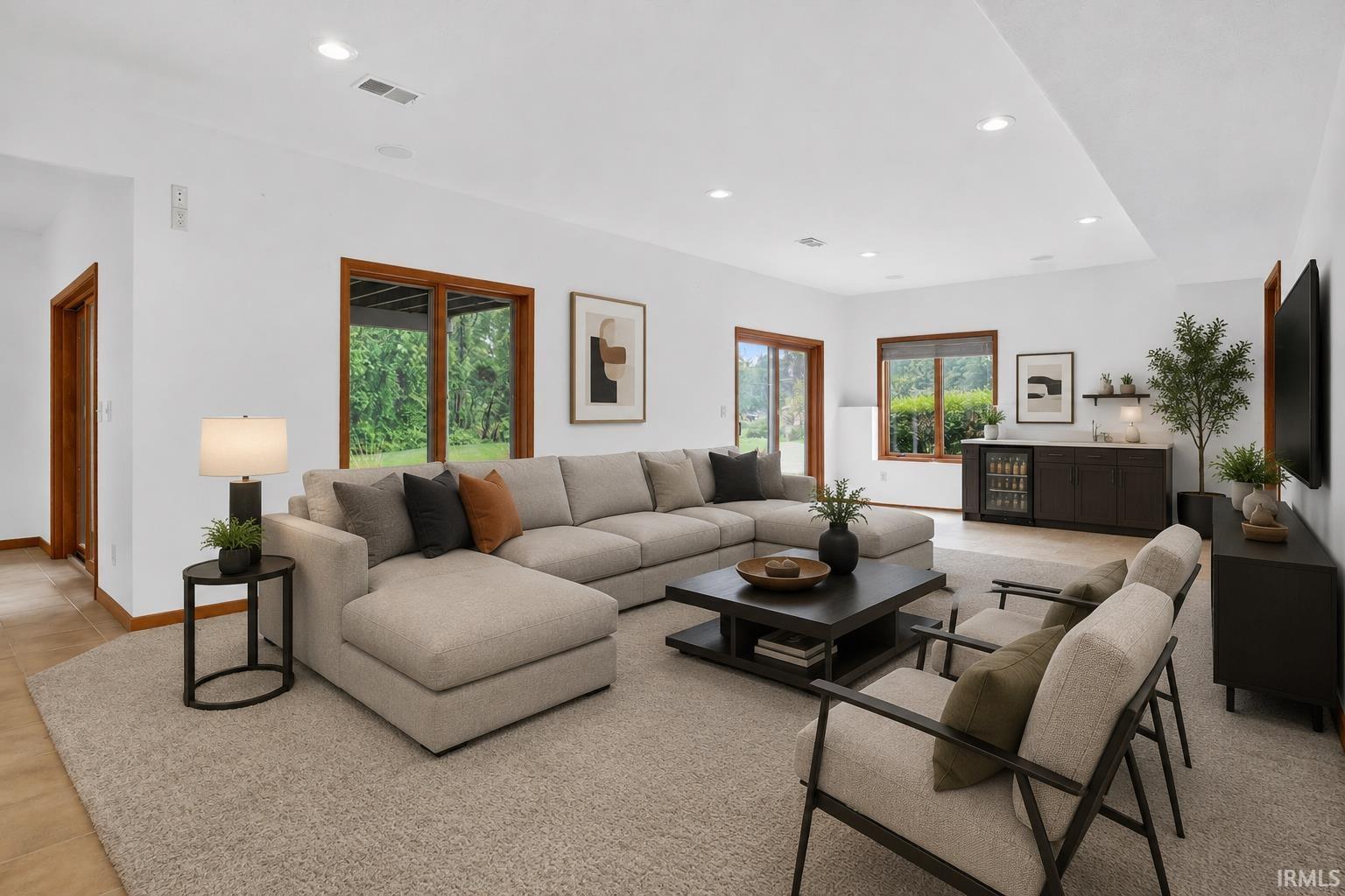 Spacious living area featuring recessed lighting, light-toned carpeting, wood-frame windows, a built-in wet bar with a beverage cooler, and a sliding glass door leading to the outdoors