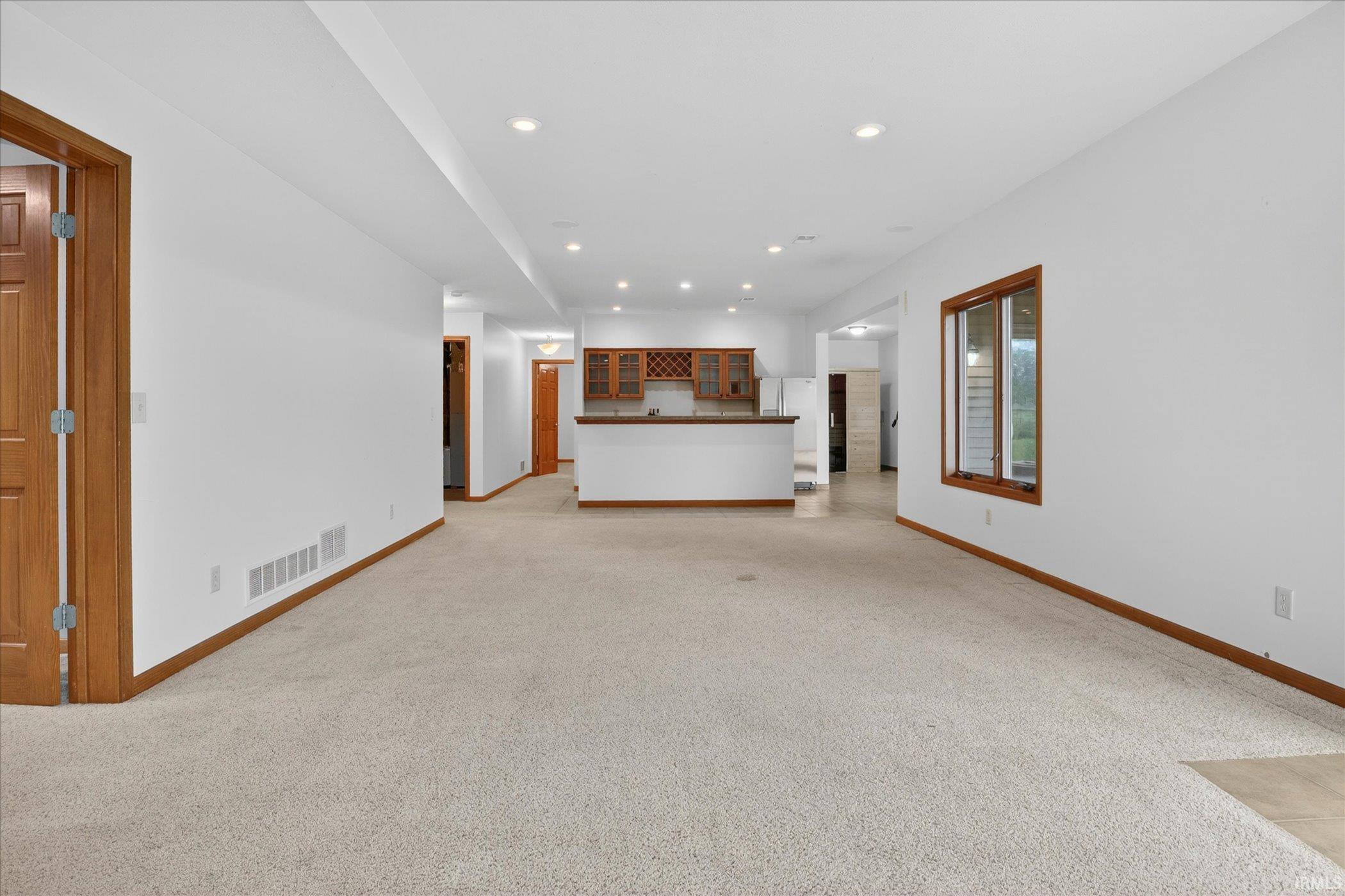 Spacious lower level featuring an integrated wet bar, recessed lighting, wood-trim windows, and an expansive carpeted area