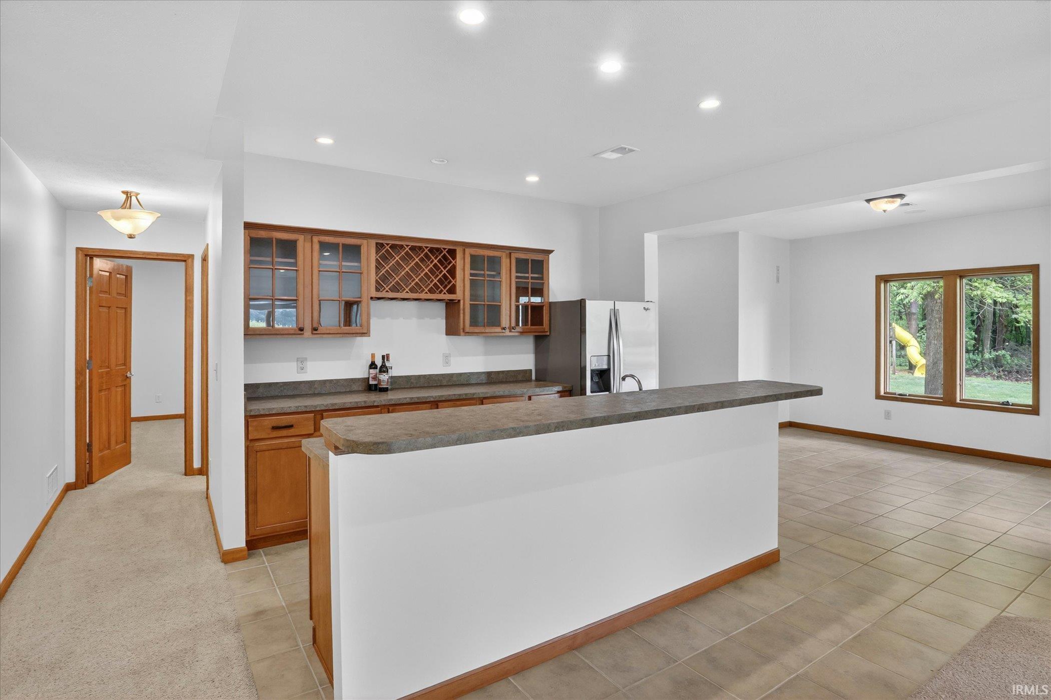 Wet bar featuring wood cabinetry, integrated wine rack, and a stone-finish countertop
