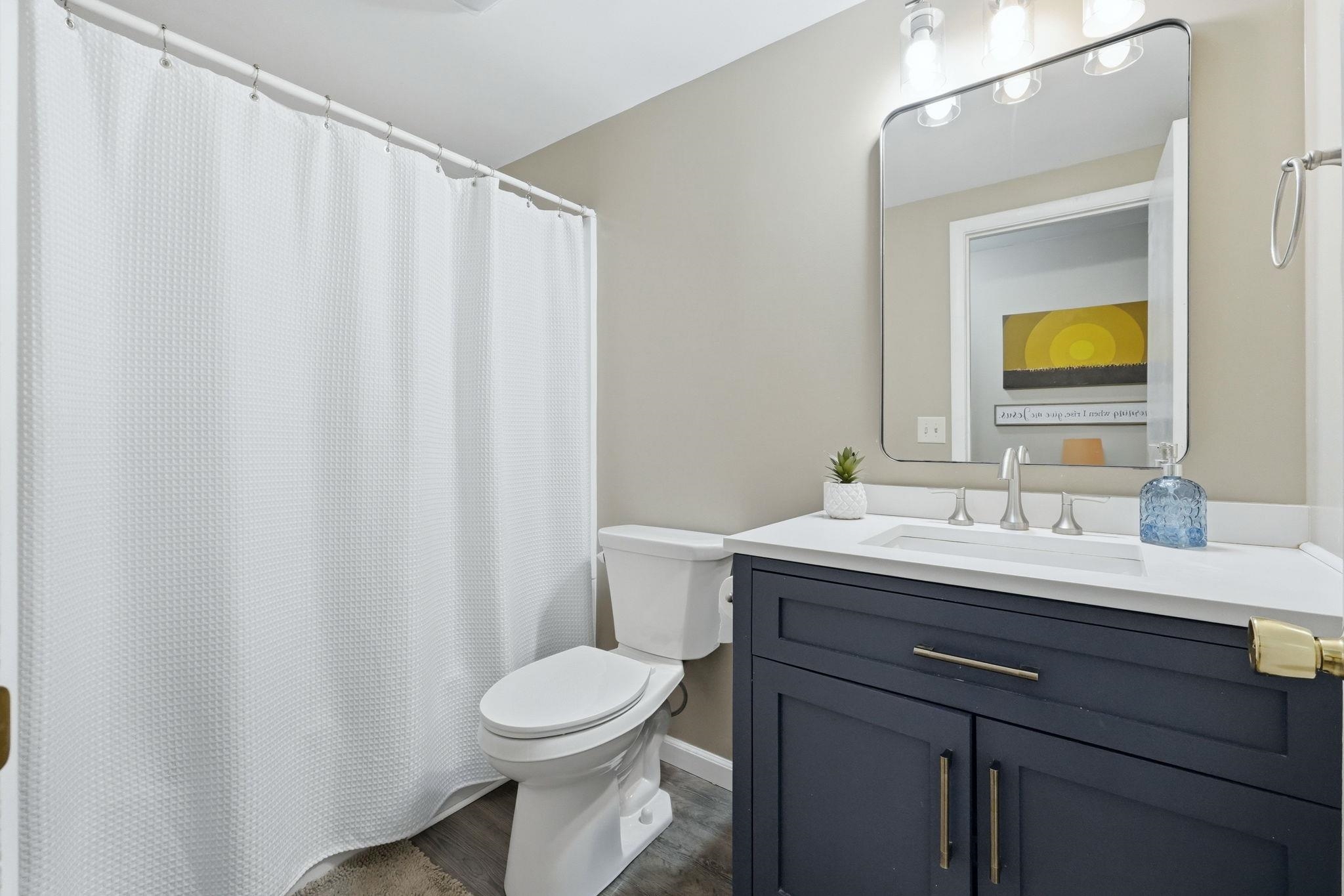 Bathroom featuring a navy blue vanity with brushed nickel hardware, white countertop, and an undermount sink