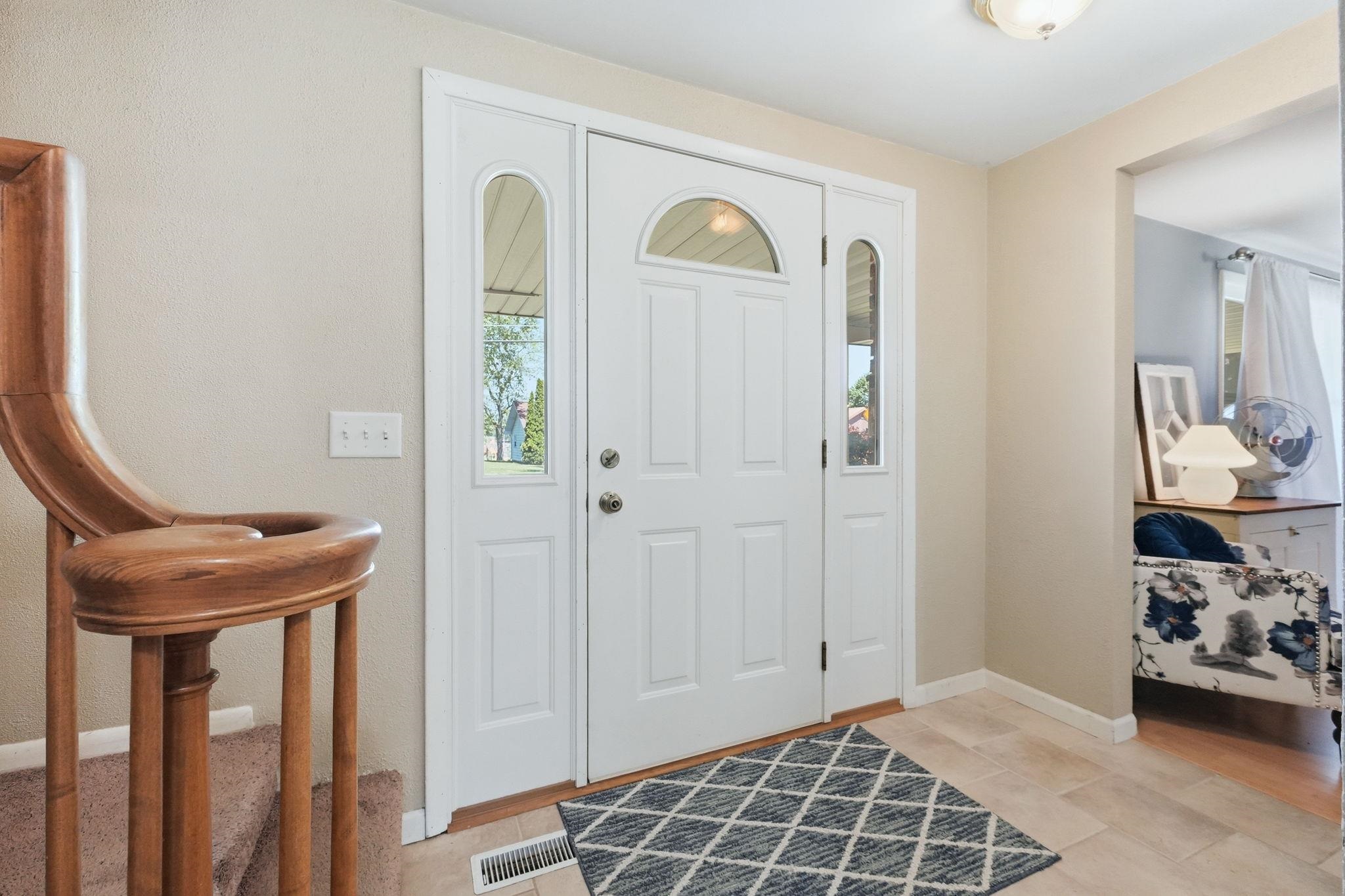 Entryway featuring a white paneled door with an arched transom window and two sidelights