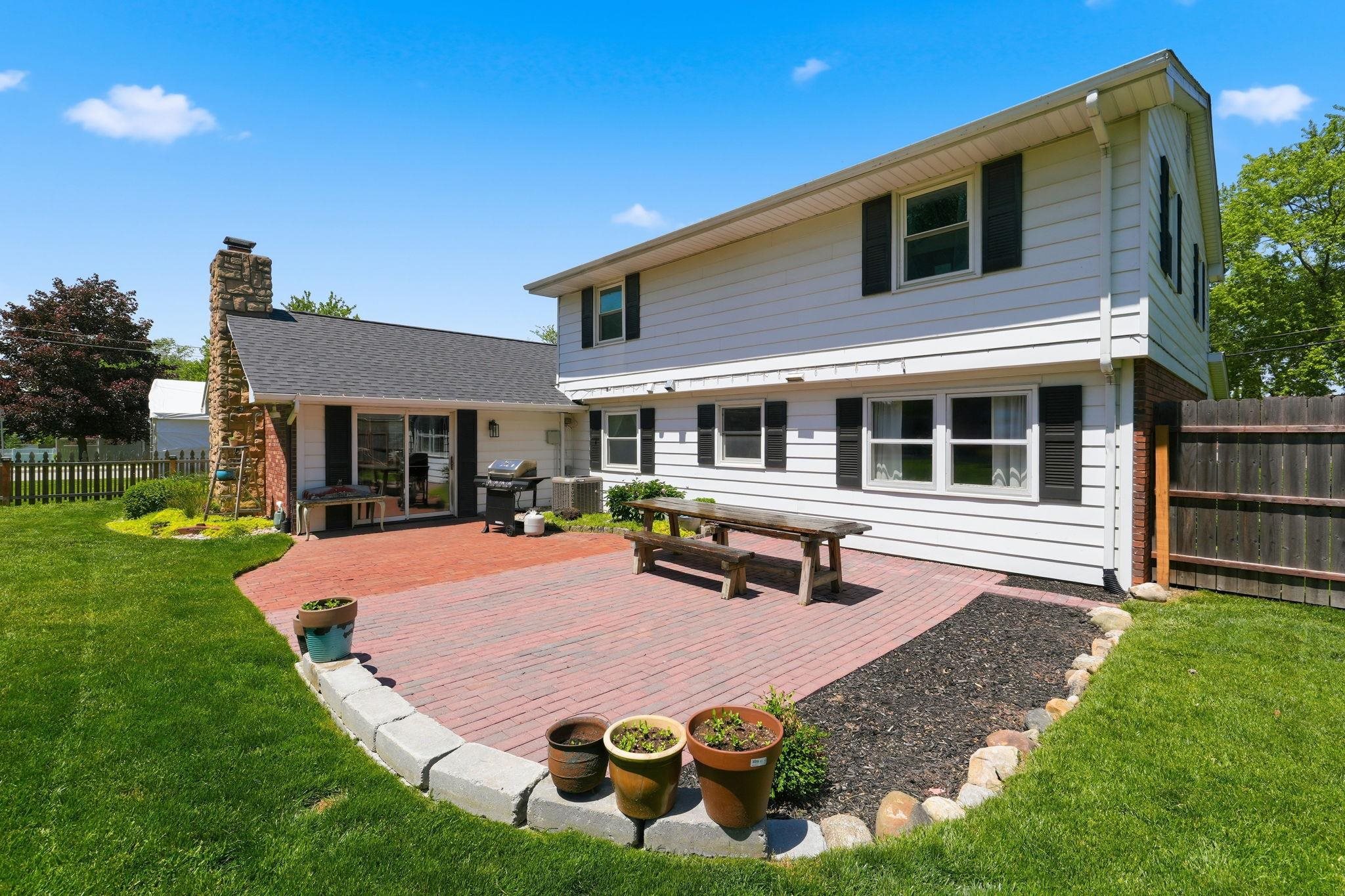 Spacious brick patio with a stone perimeter and mature landscaping