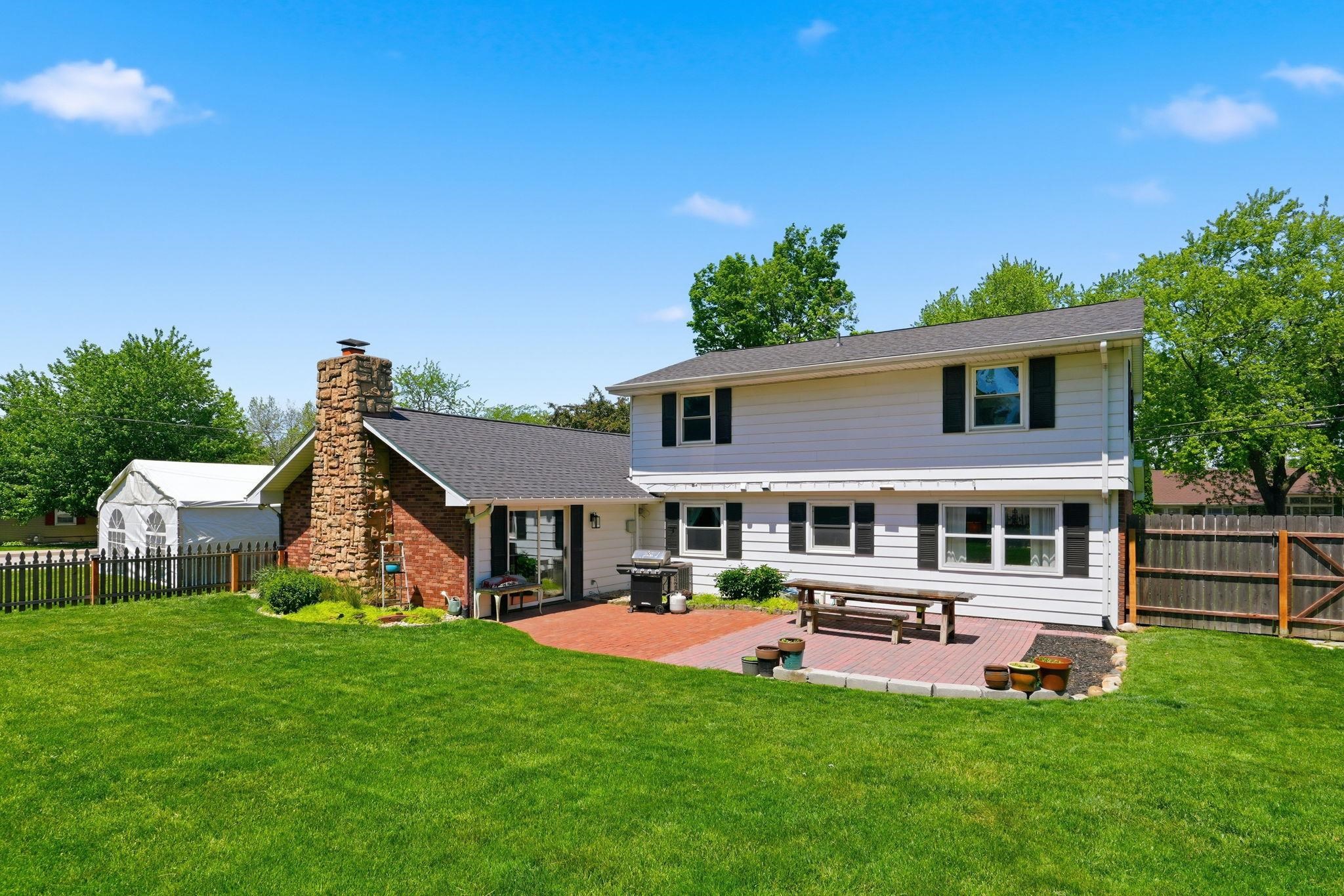 Expansive backyard featuring a brick paver patio, stone chimney, and a full privacy fence
