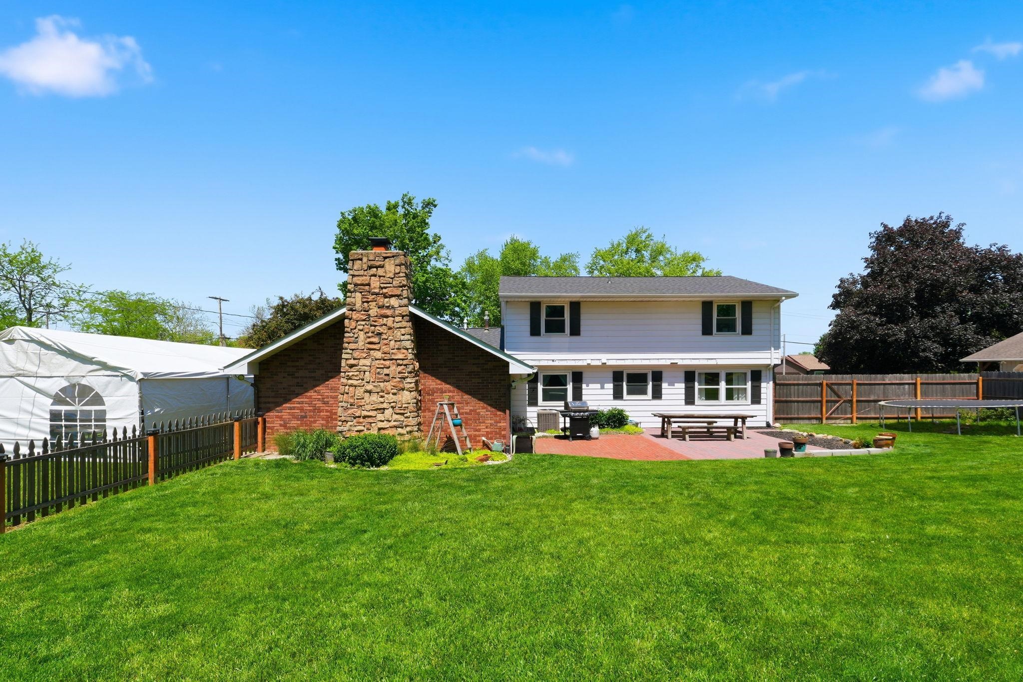 Expansive green lawn with a white two-story house featuring black shutters