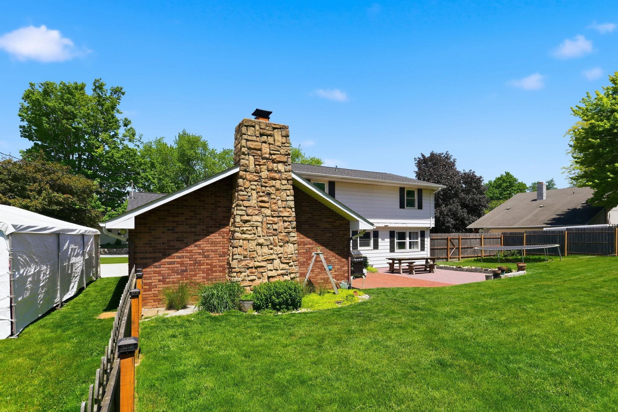 Expansive backyard featuring a stone-clad chimney and a brick-paneled exterior
