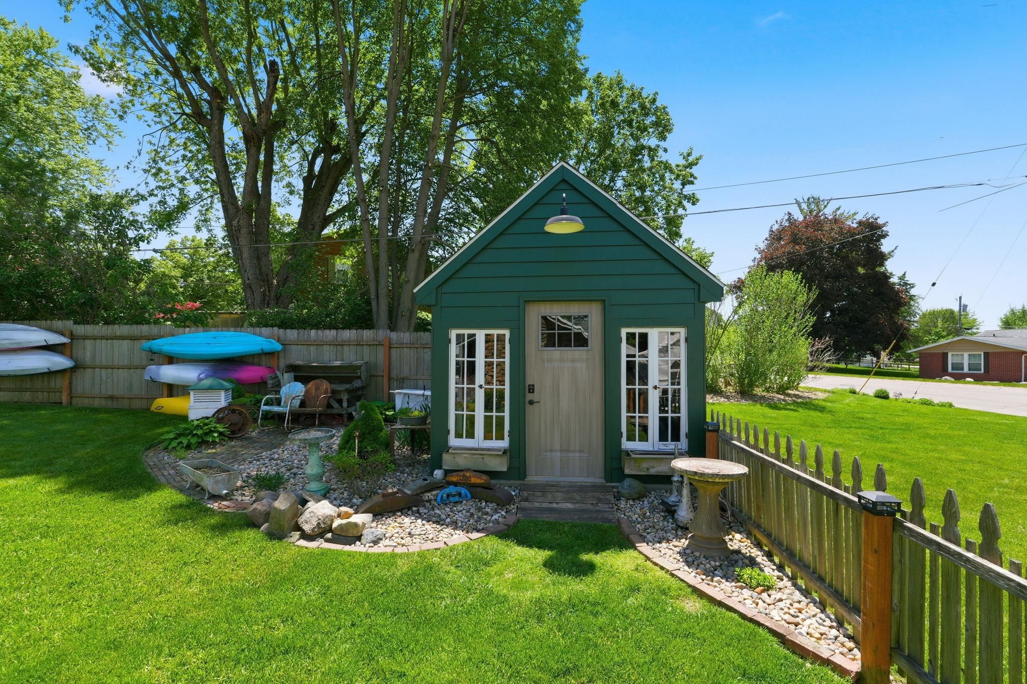 Detached green outbuilding featuring shiplap siding and a gable roofline