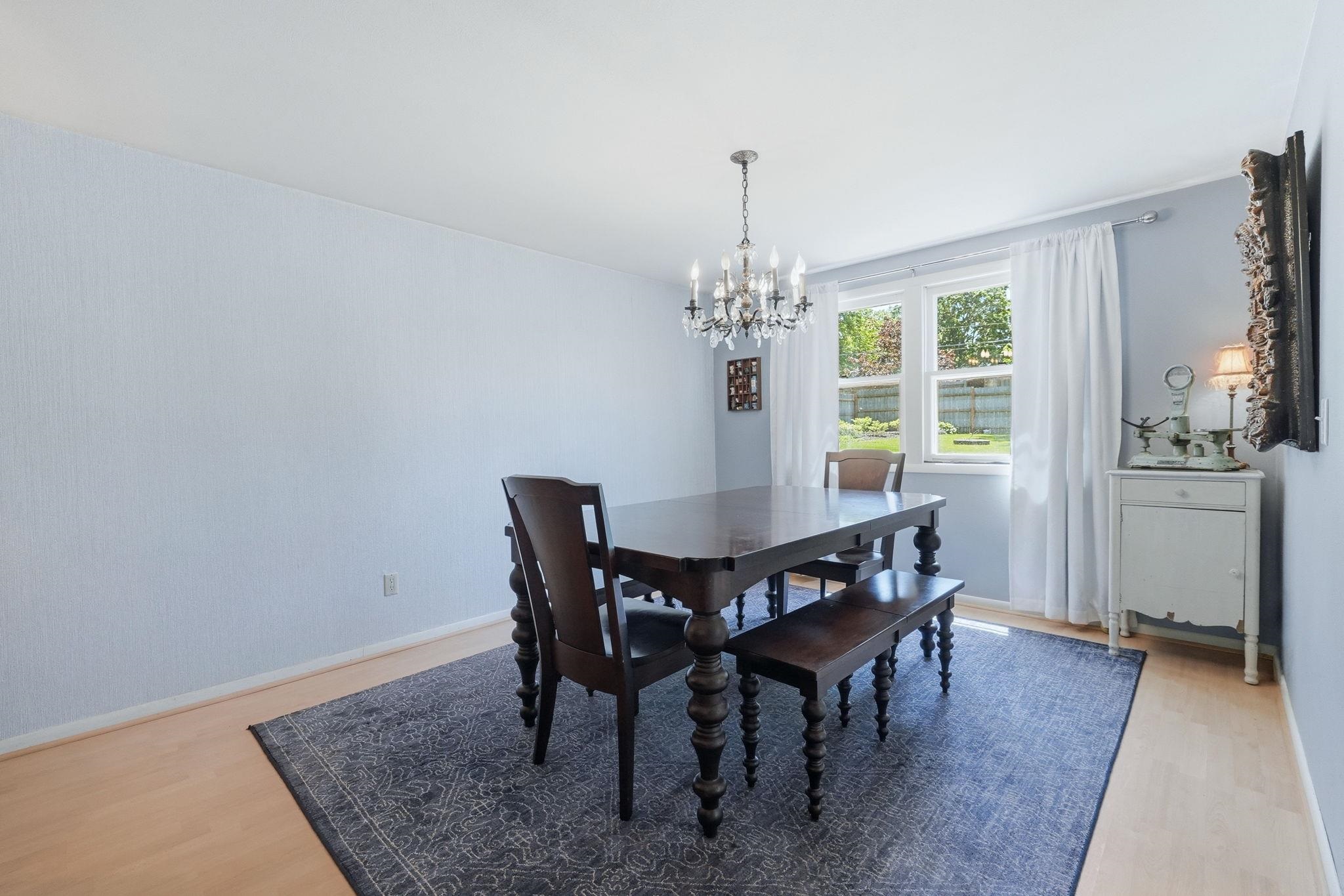 Dining area featuring light wood-finish flooring, a multi-pane window, and a decorative chandelier