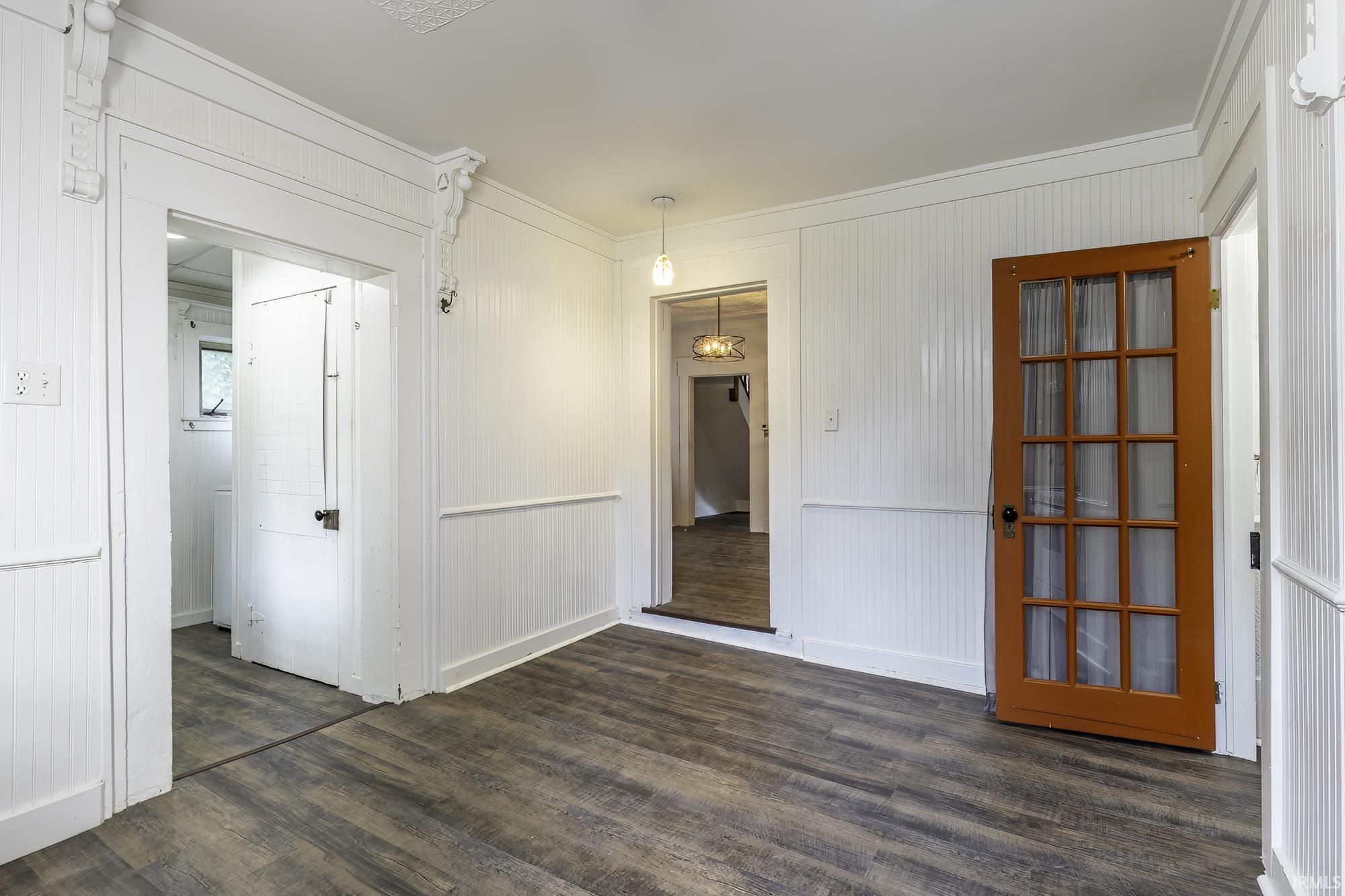 Interior space featuring wood-finish flooring, white beadboard paneling, and decorative trim