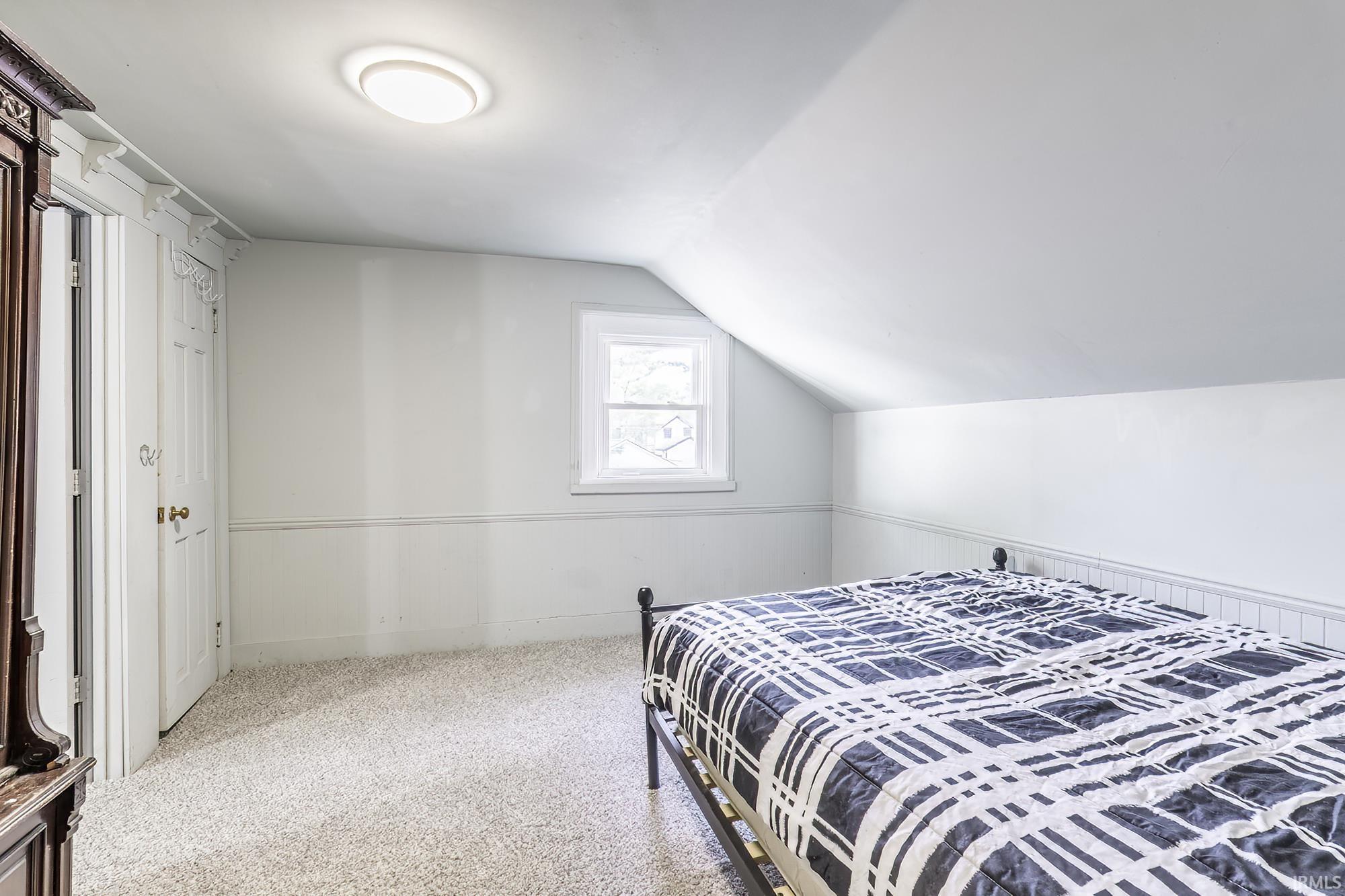 Carpeted room with a pitched ceiling and a single window