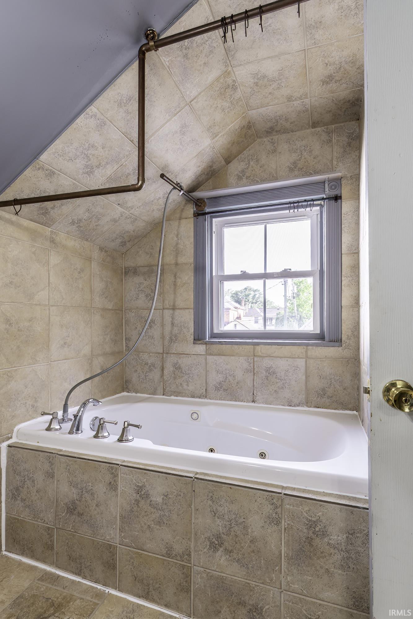 Soaking tub with integrated jets, surrounded by tiled walls and a coordinating tiled tub deck