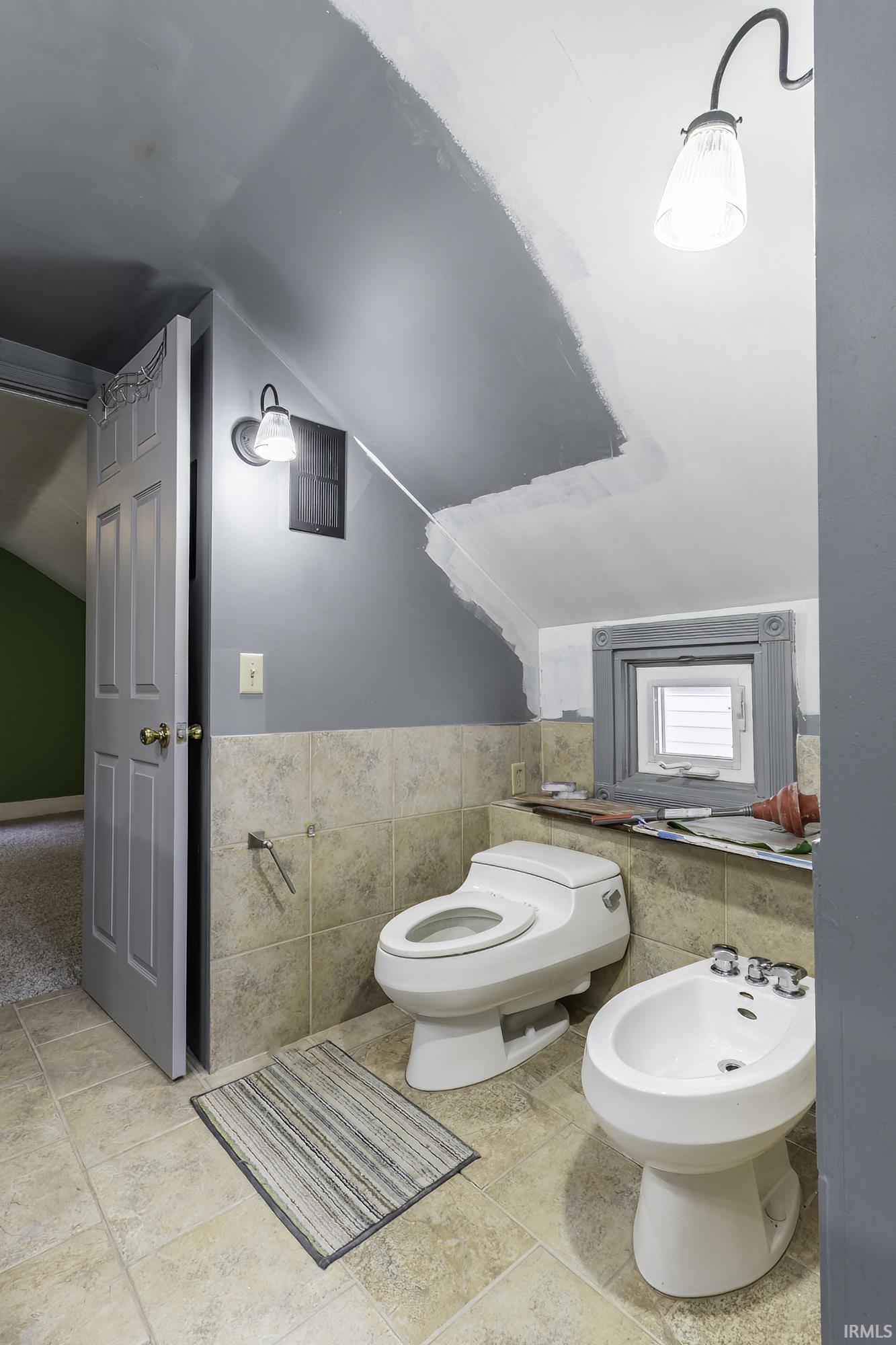 Bathroom featuring a toilet, bidet, and tiled flooring
