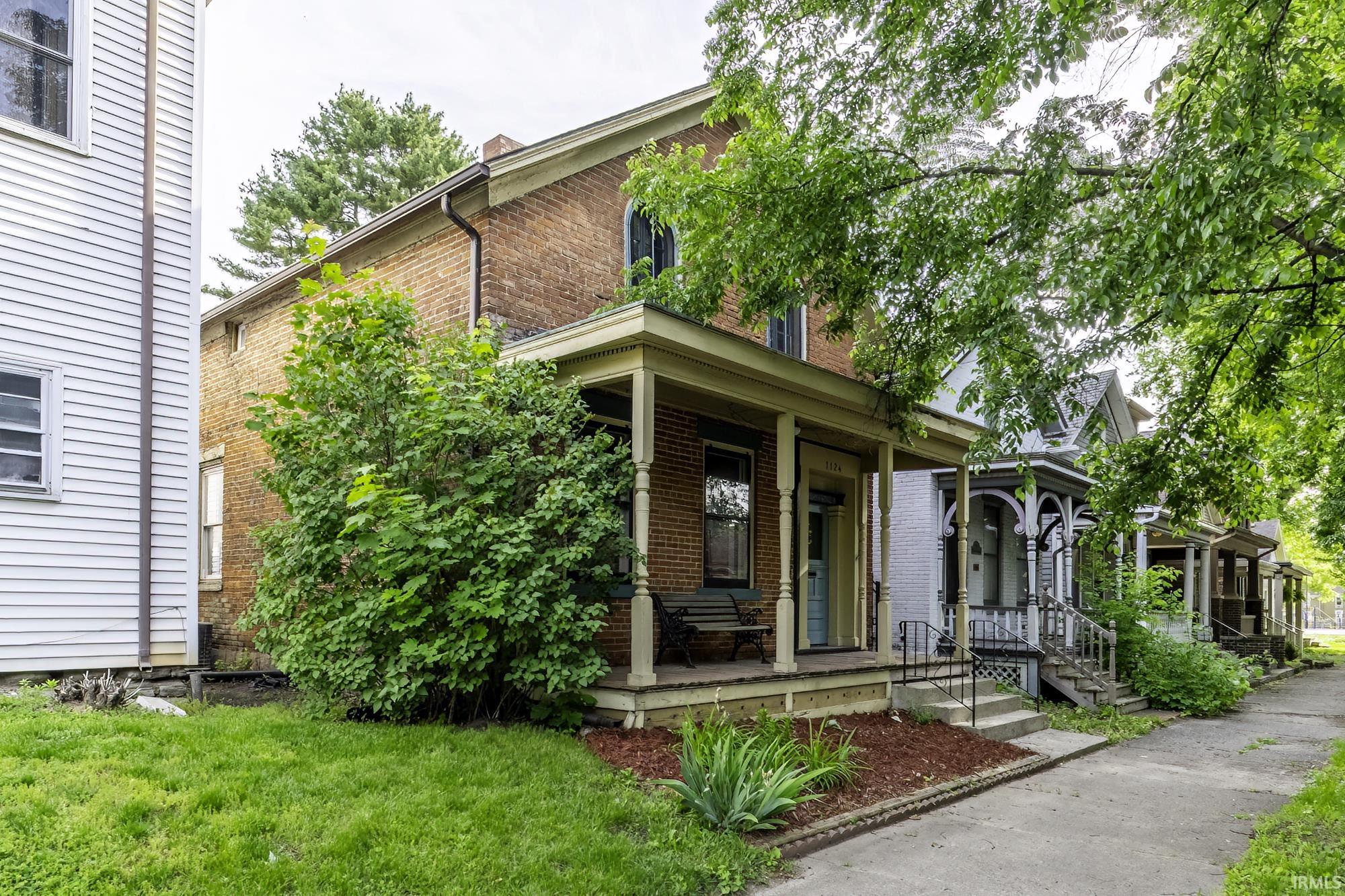 Brick exterior architecture featuring a covered front porch with column supports and a light blue entry door