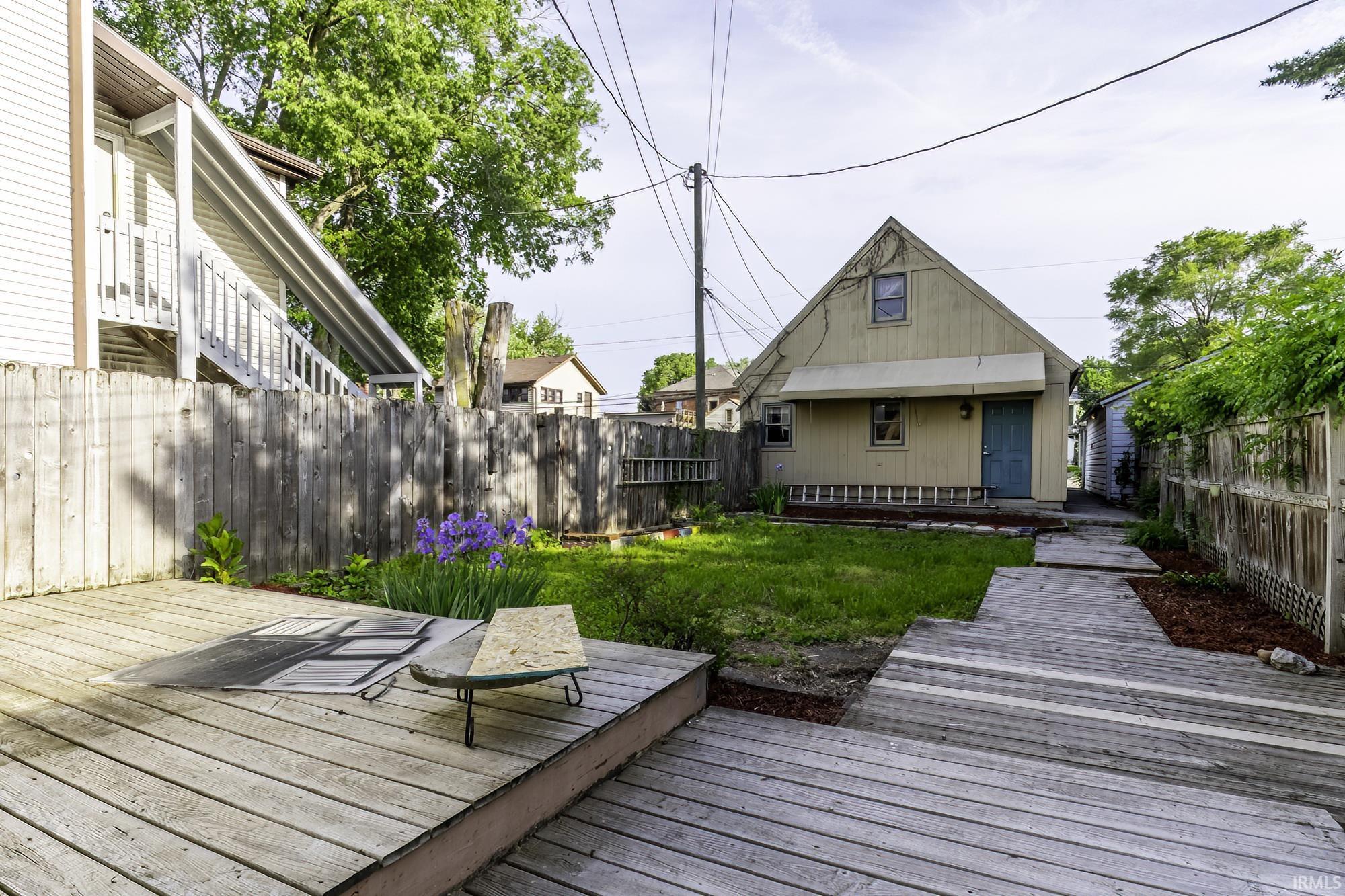 Expansive backyard featuring a multi-level wood deck, a wooden fence, and mature trees
