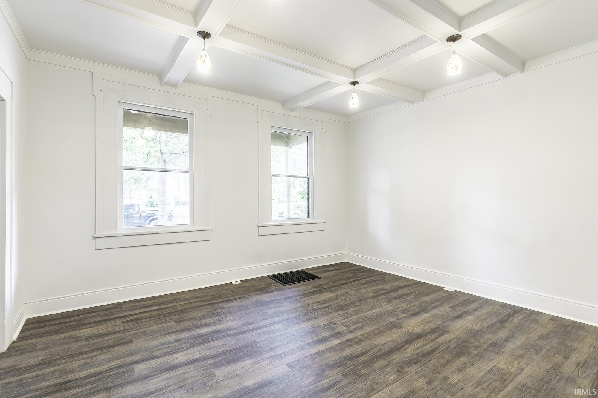 Room featuring wood-finish flooring, two large windows with white trim, white walls, and a white coffered ceiling with recessed lighting