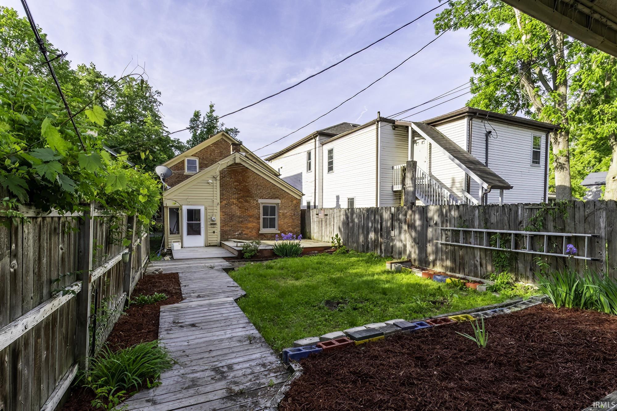 Rear exterior featuring a brick and siding facade with a wooden deck