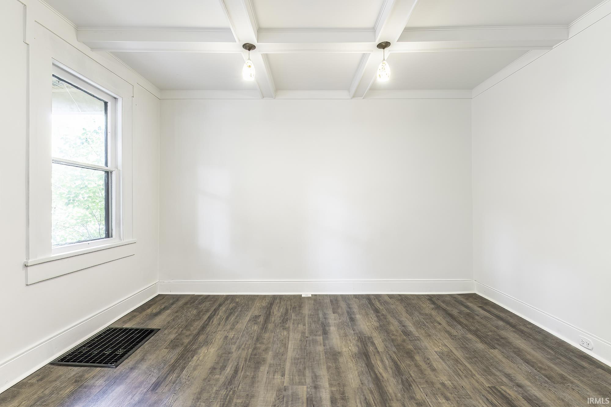 Interior space featuring wood-finish flooring, white walls, and a single window with white trim