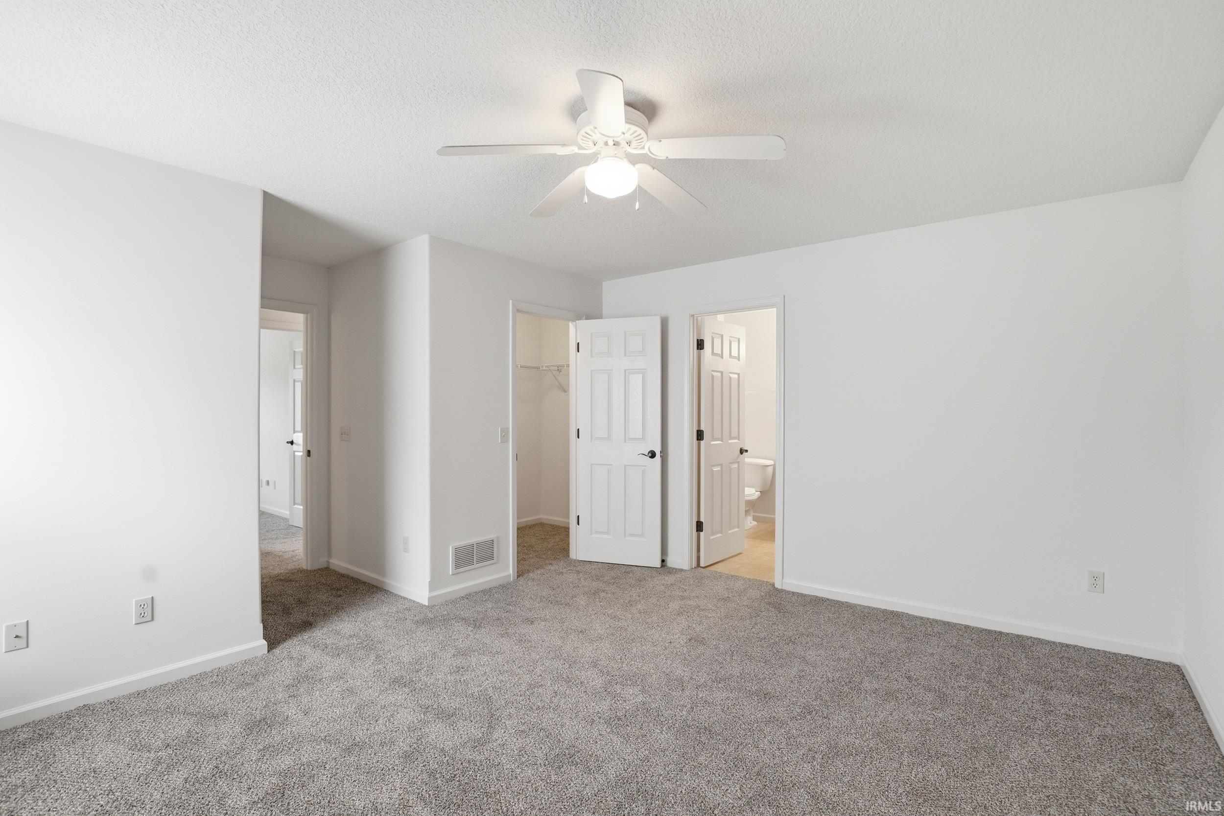 Spacious room featuring neutral carpeting and white walls