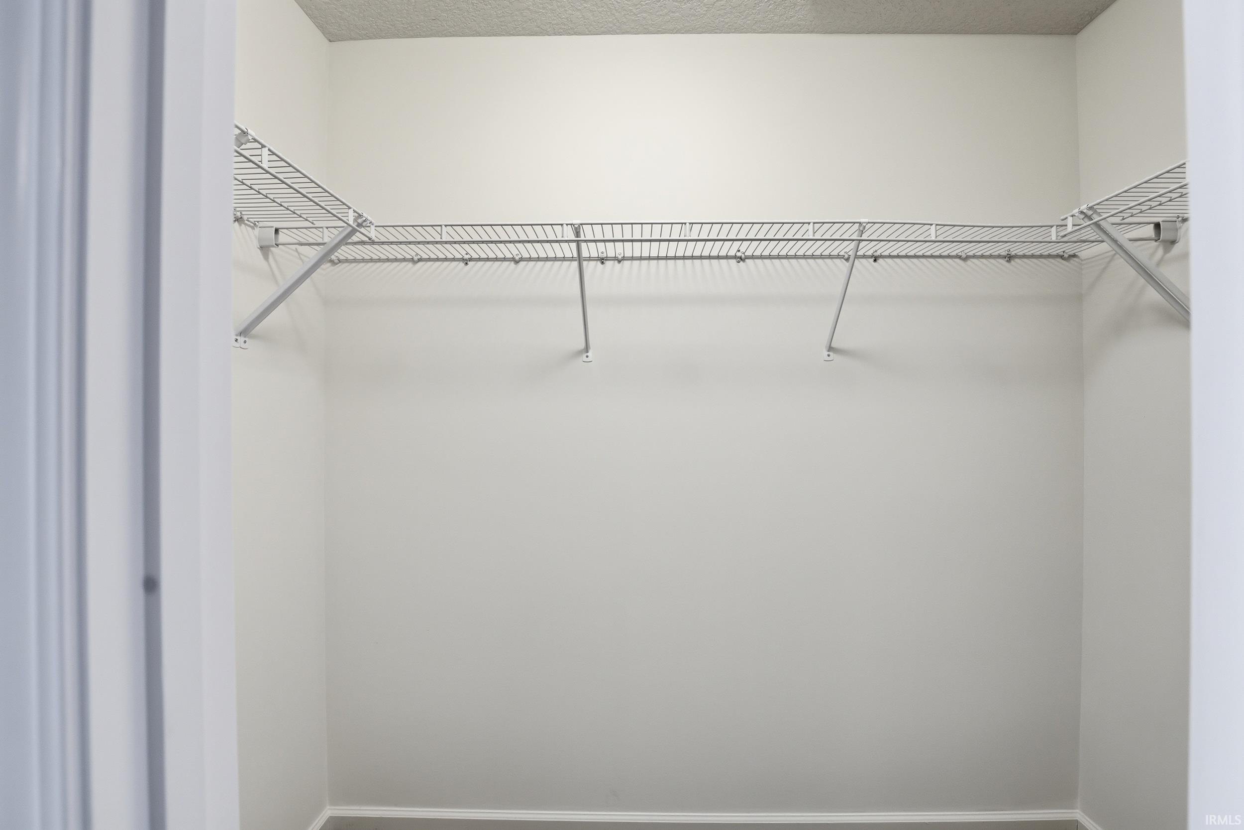 Interior closet featuring wire shelving system, white wall paint, and light-colored baseboards