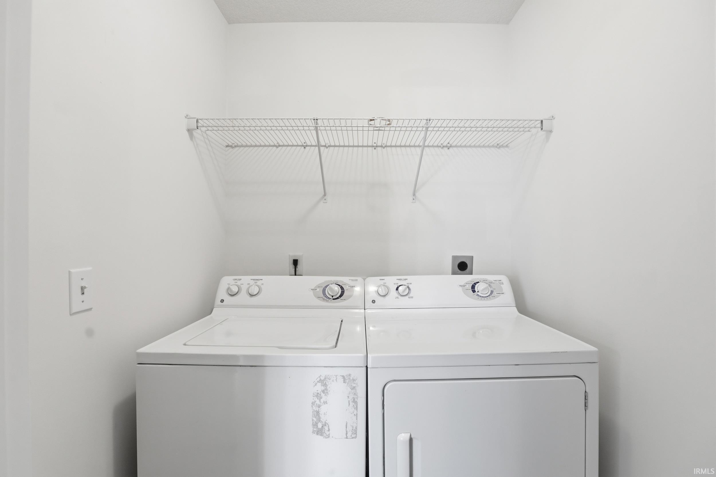 Dedicated laundry area featuring white walls and a wire shelving unit
