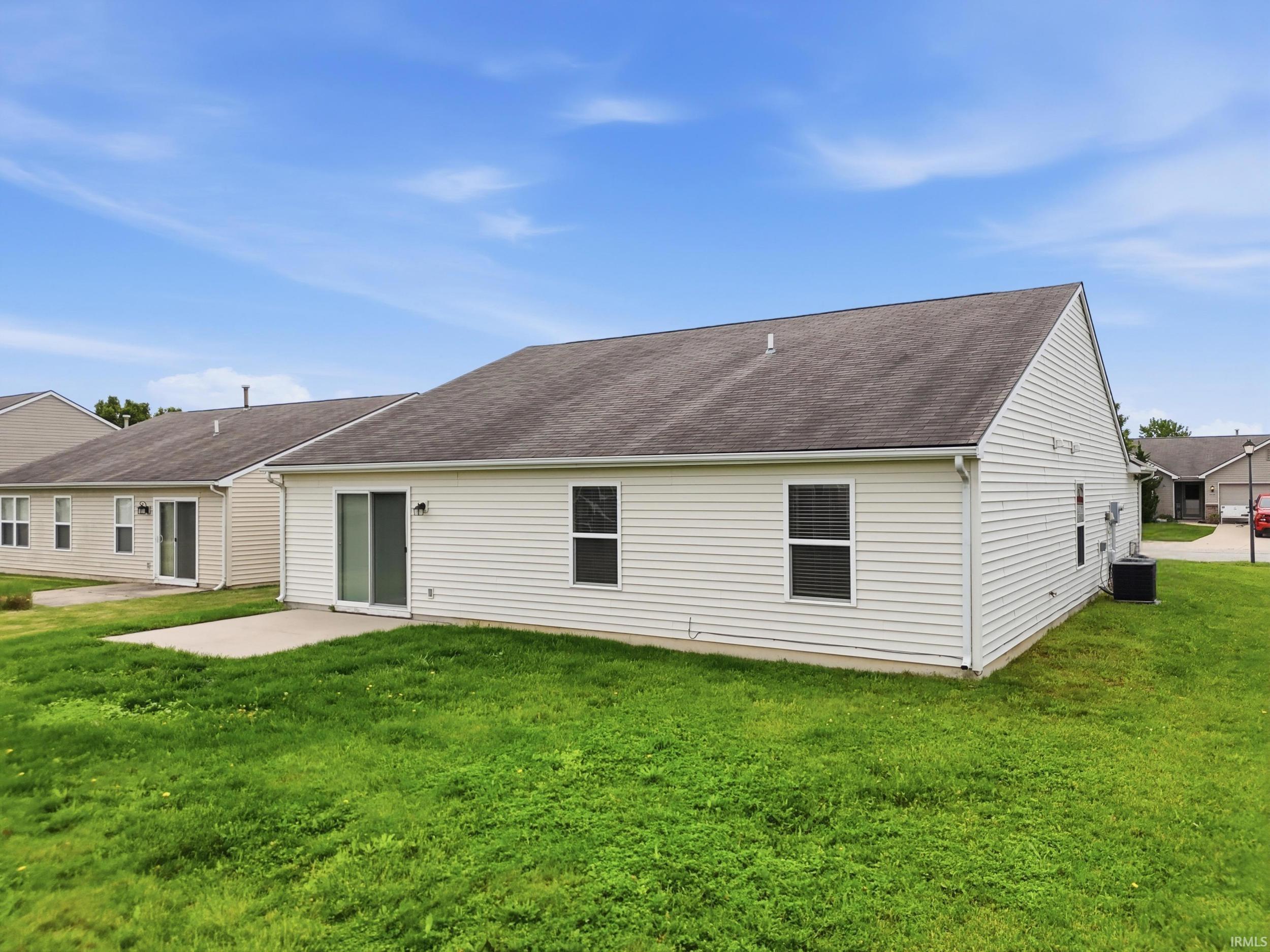 Rear exterior featuring white vinyl siding, a concrete patio, and a sliding glass door