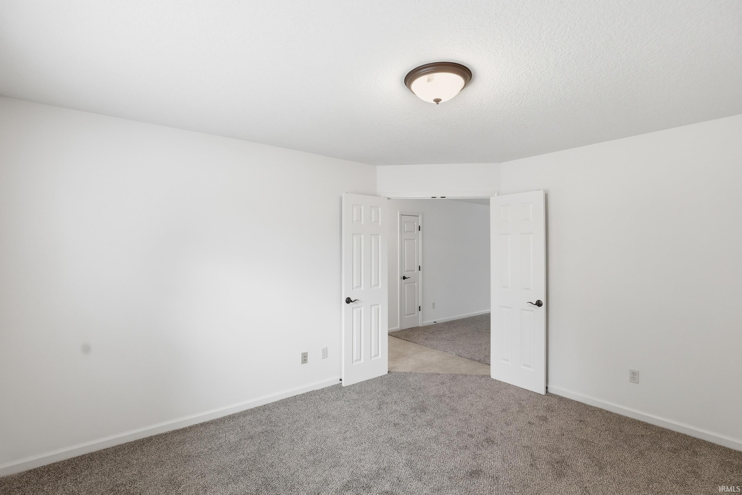Spacious room featuring neutral carpeting and white painted walls