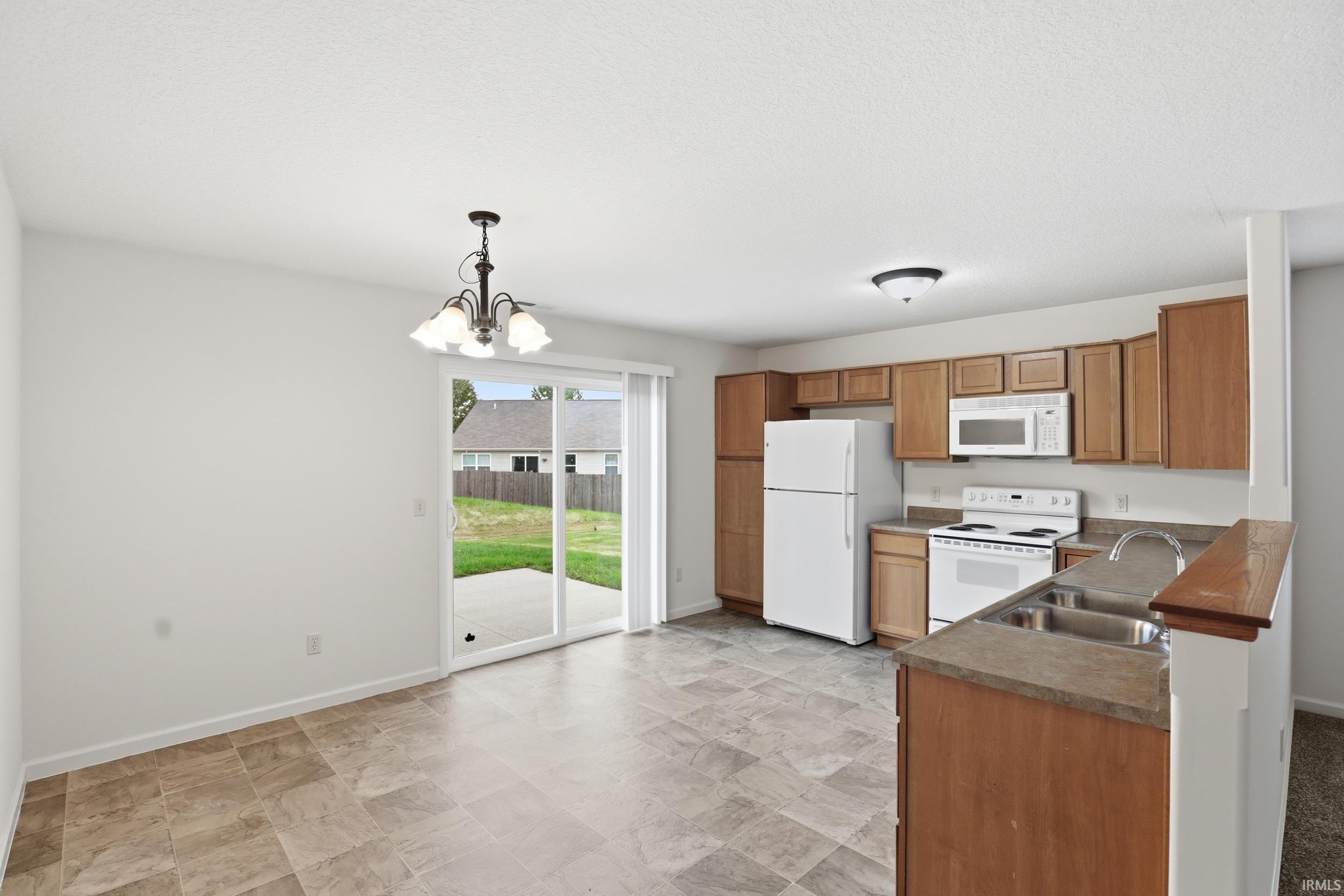 Kitchen and dining area featuring wood cabinetry, white appliances, and a dual basin sink