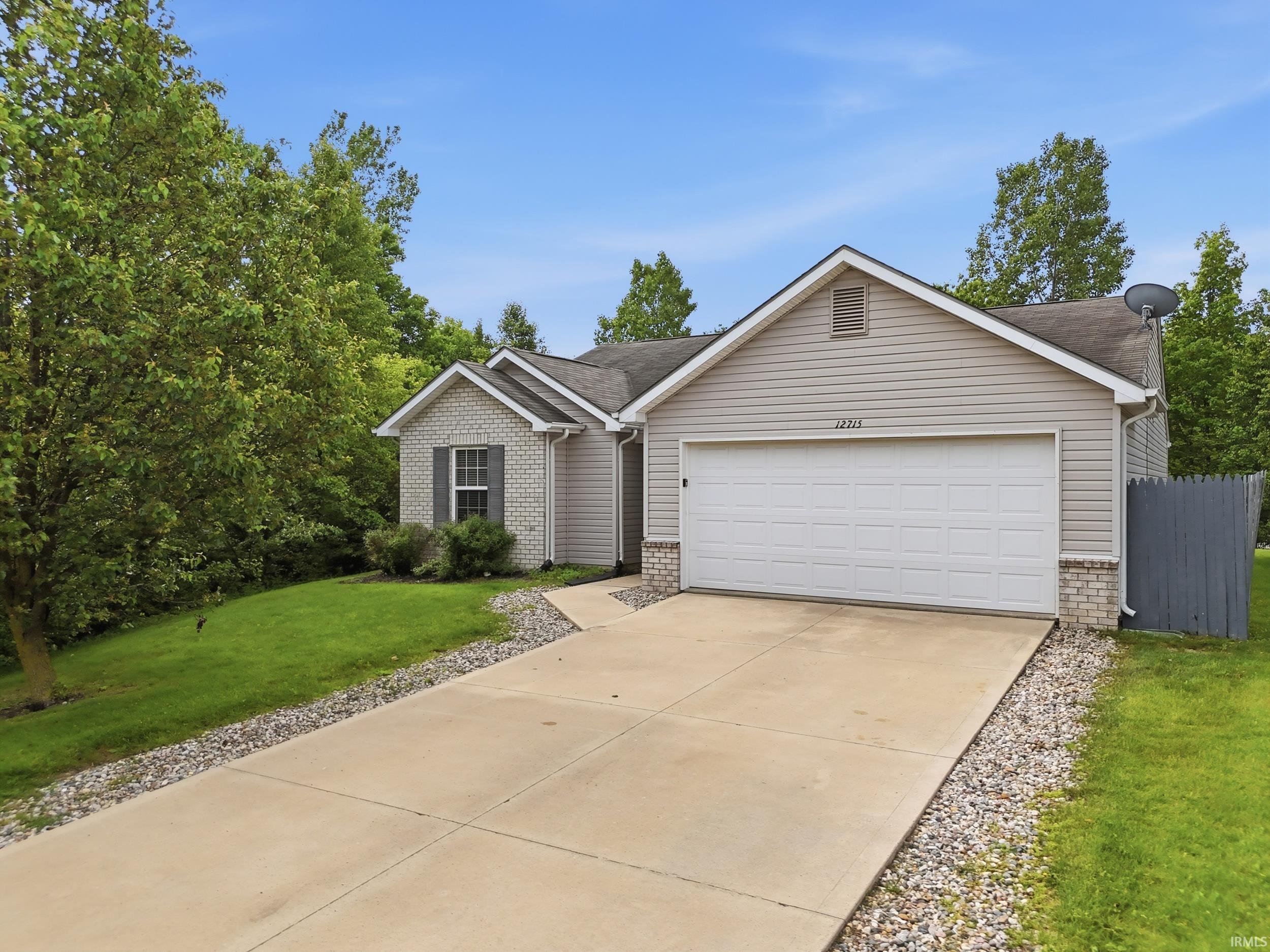 Exterior featuring light-colored siding, partial brick facade, and a two-car garage