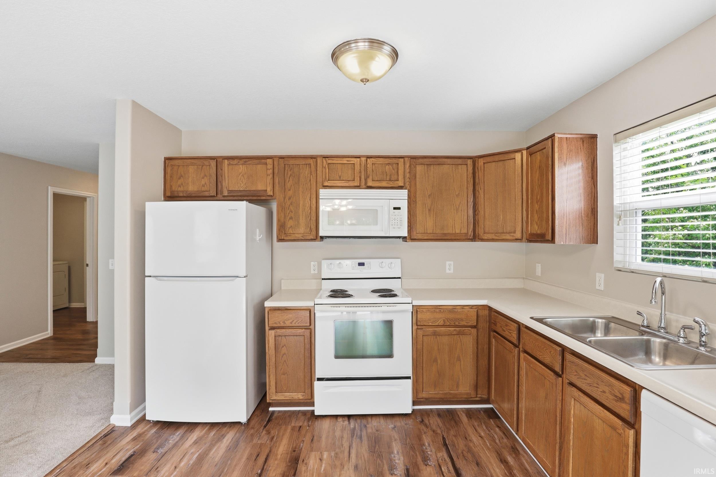 Kitchen featuring wood-finish flooring, wood cabinetry, laminate countertops, and a double basin stainless steel sink