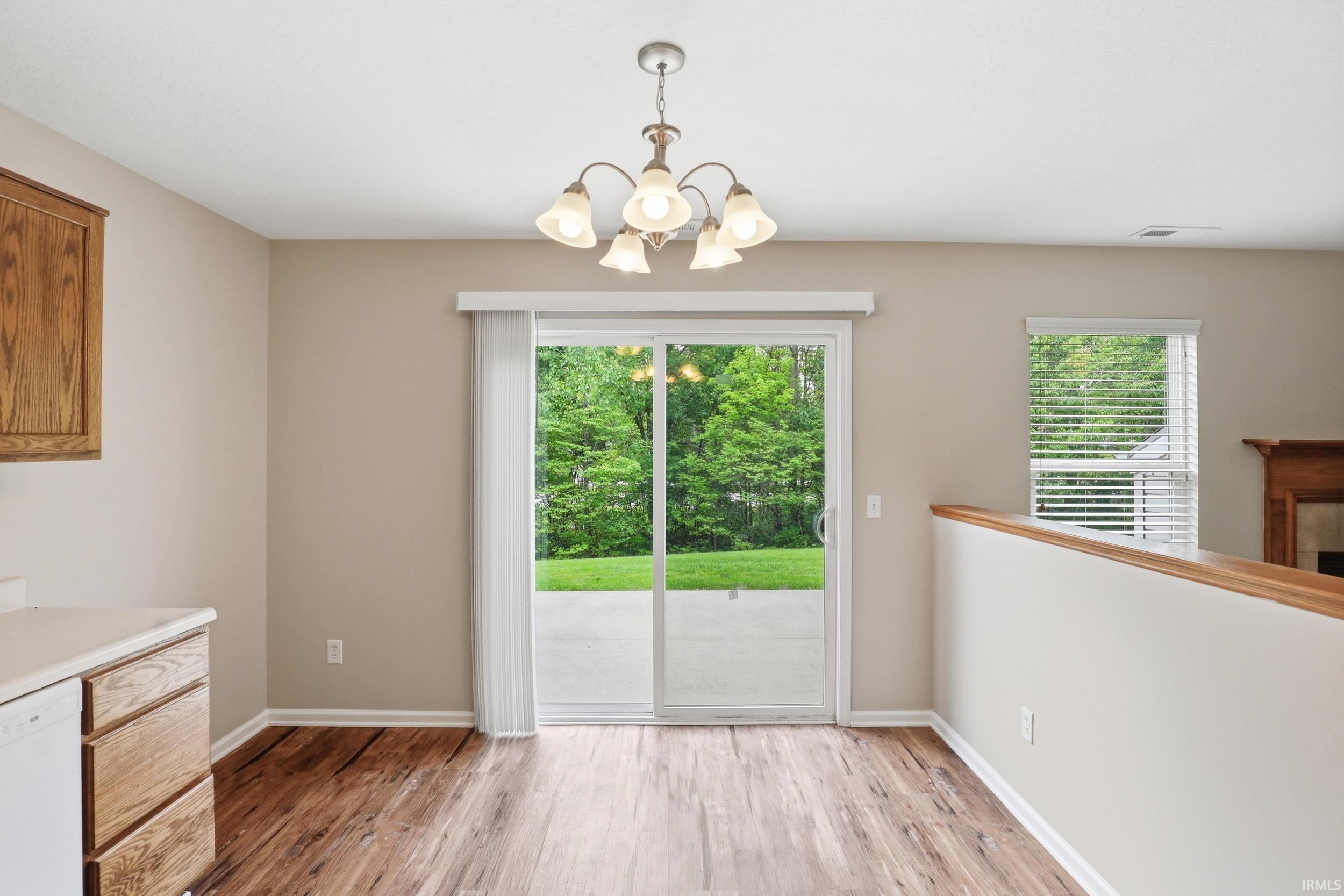 Dining area featuring wood-finish flooring, a contemporary chandelier, and a sliding glass door providing direct patio access