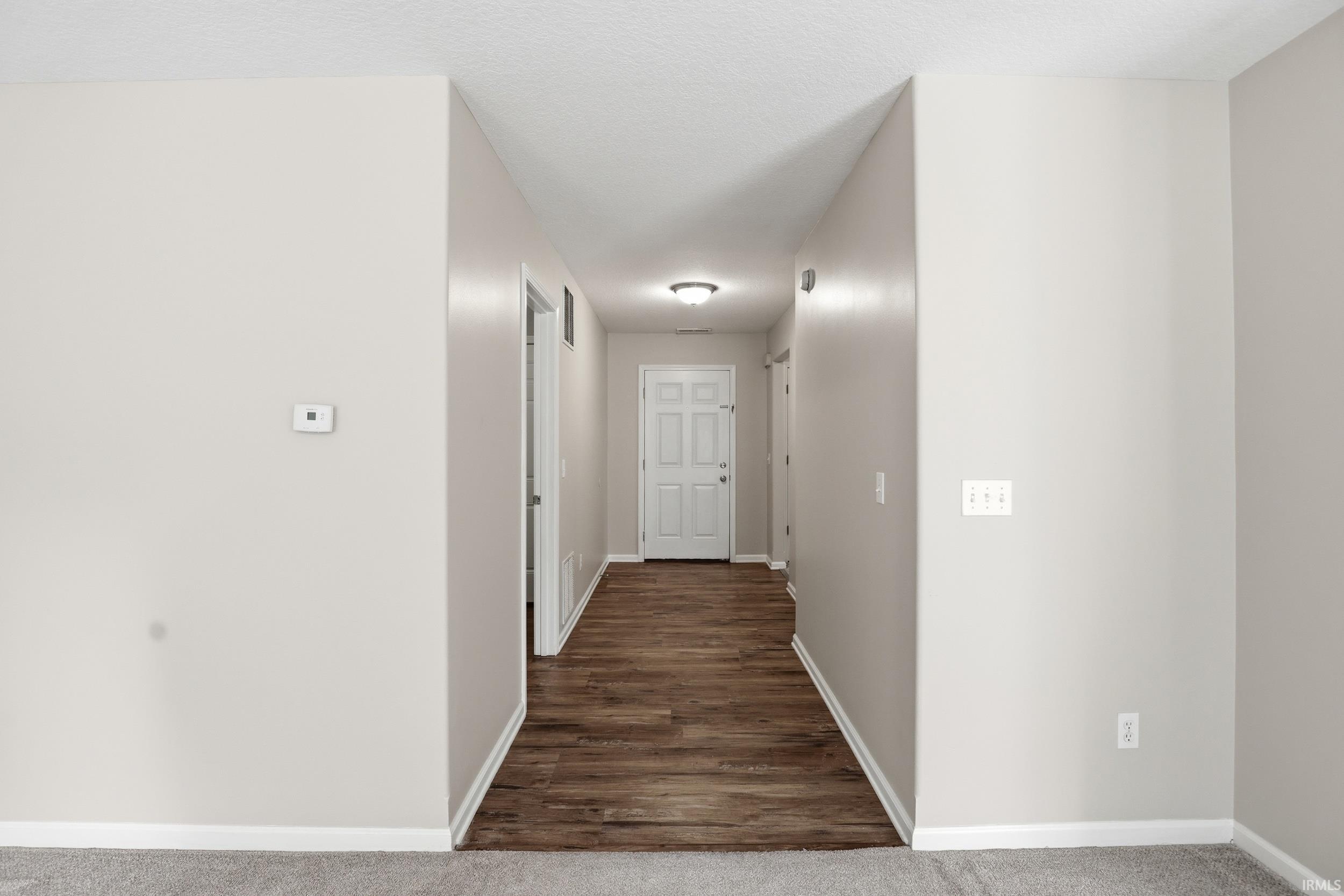 Hallway featuring wood-finish flooring and light neutral wall paint