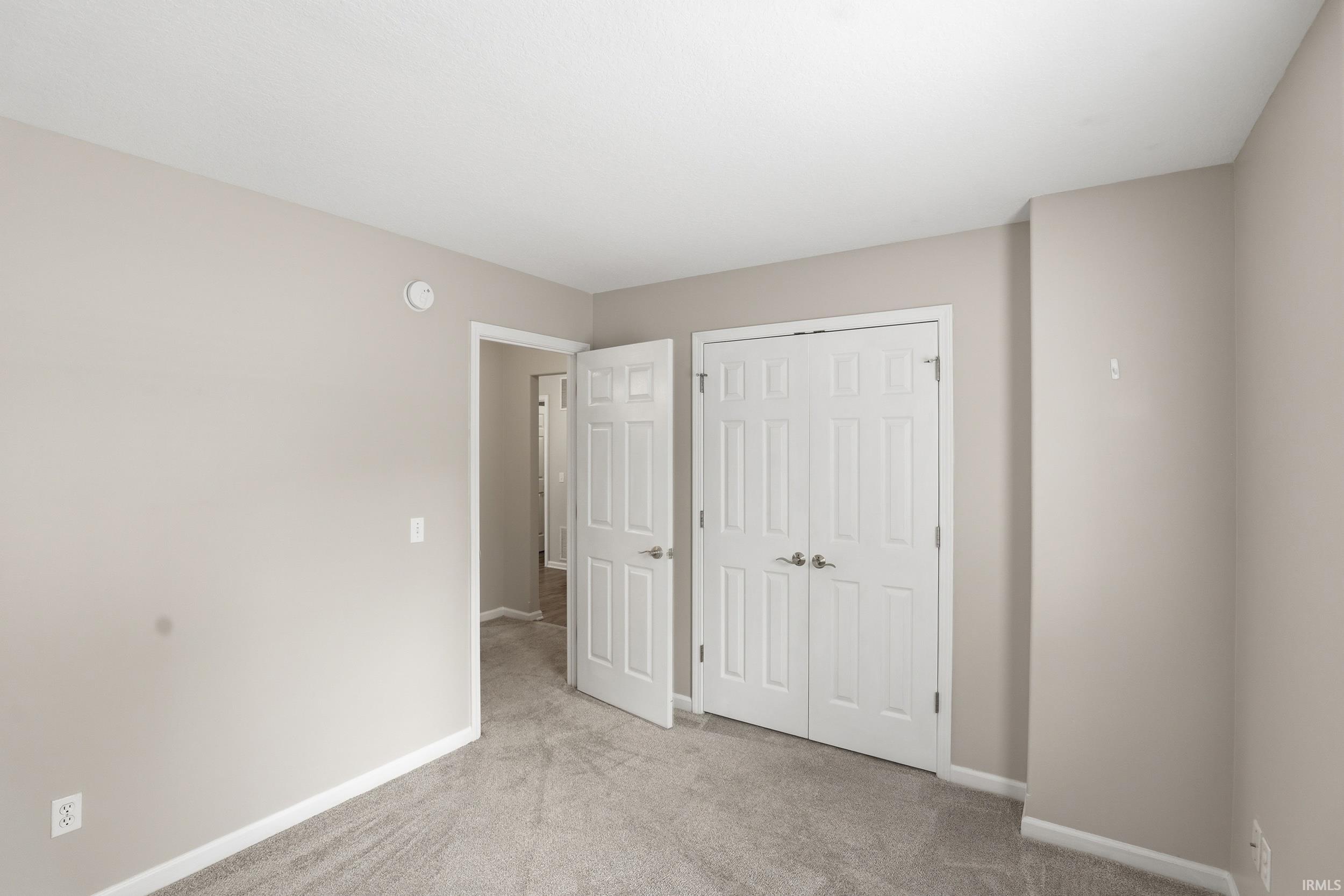 Carpeted room featuring a white ceiling, light neutral wall paint, and white baseboards