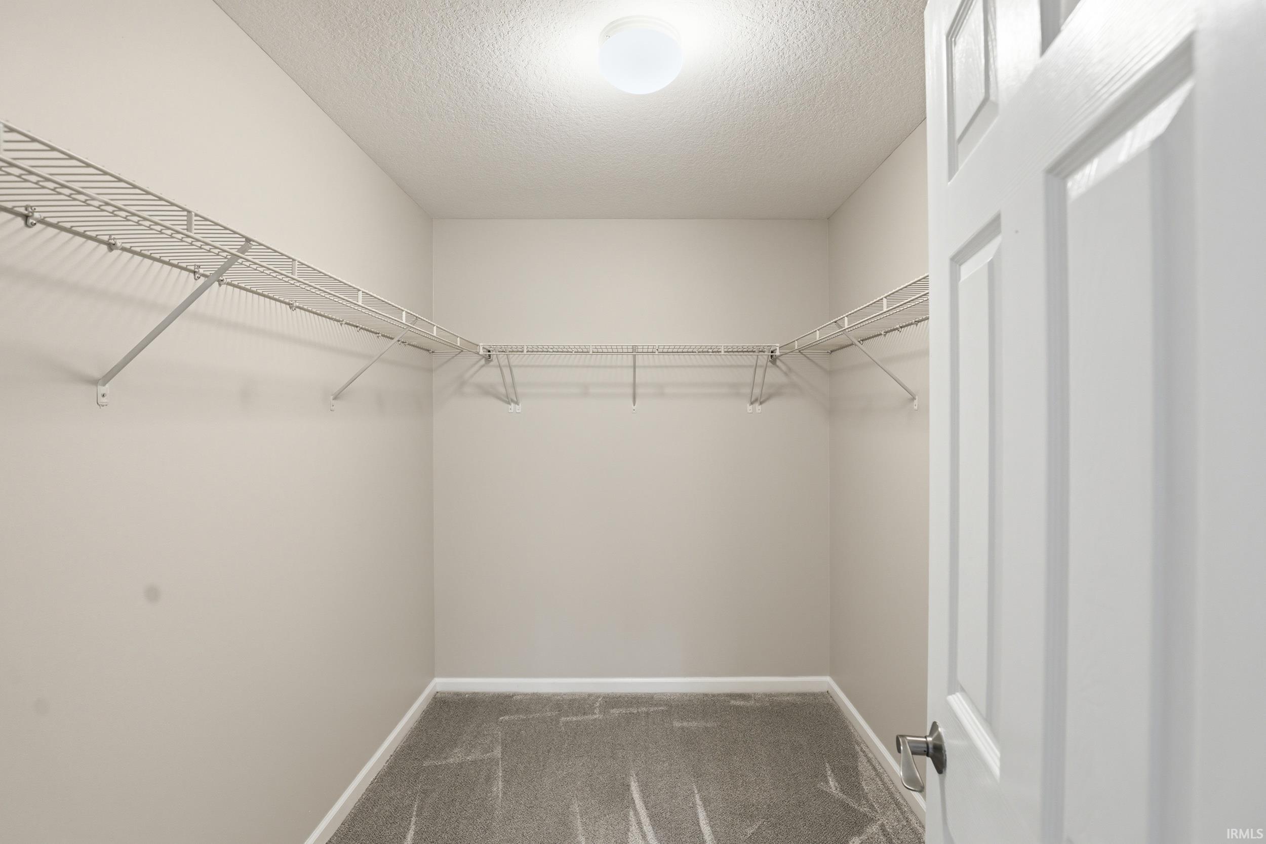 Spacious walk-in closet featuring wire shelving and hanging rods