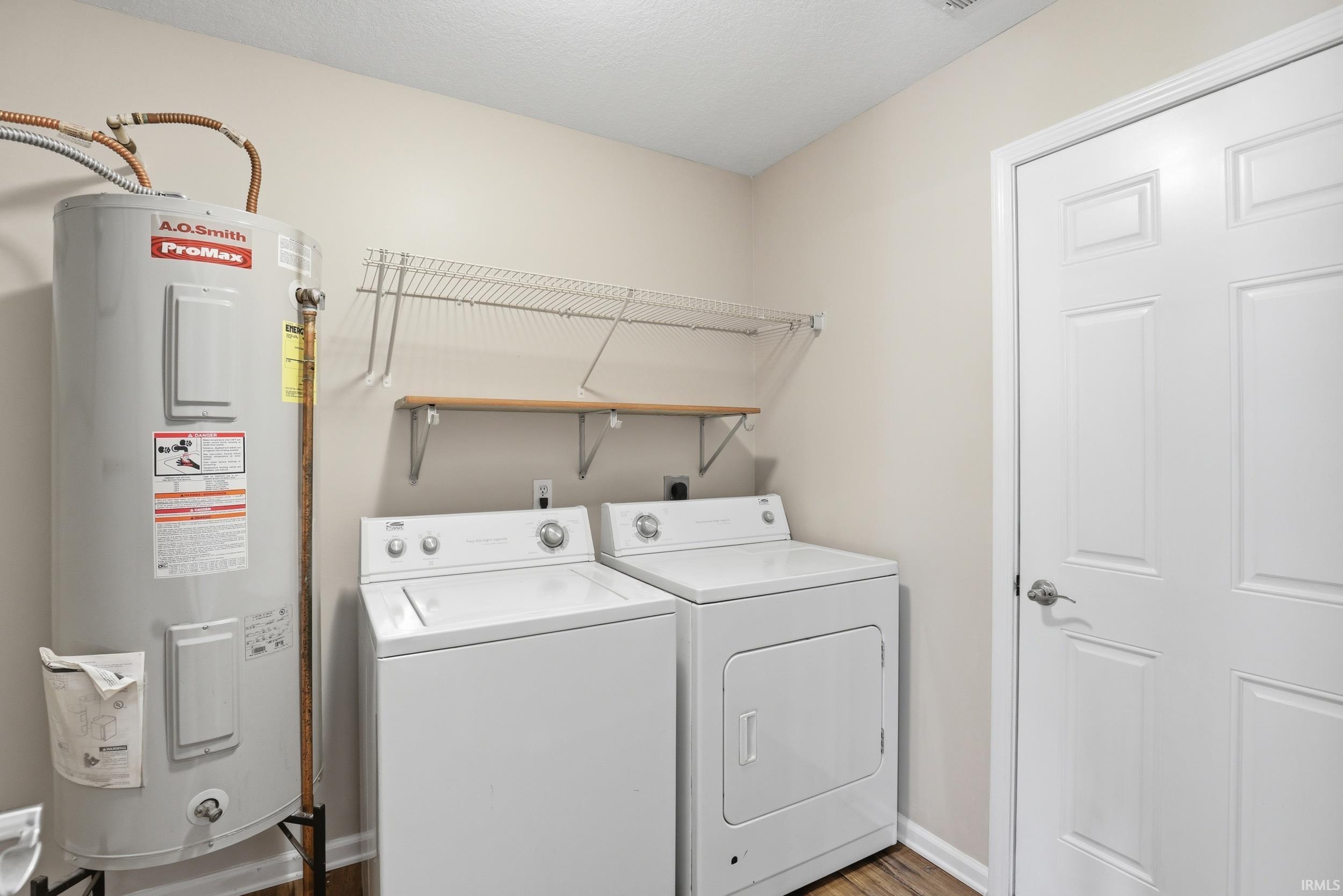 Utility area with wood-finish flooring, two white appliances, and a water heater