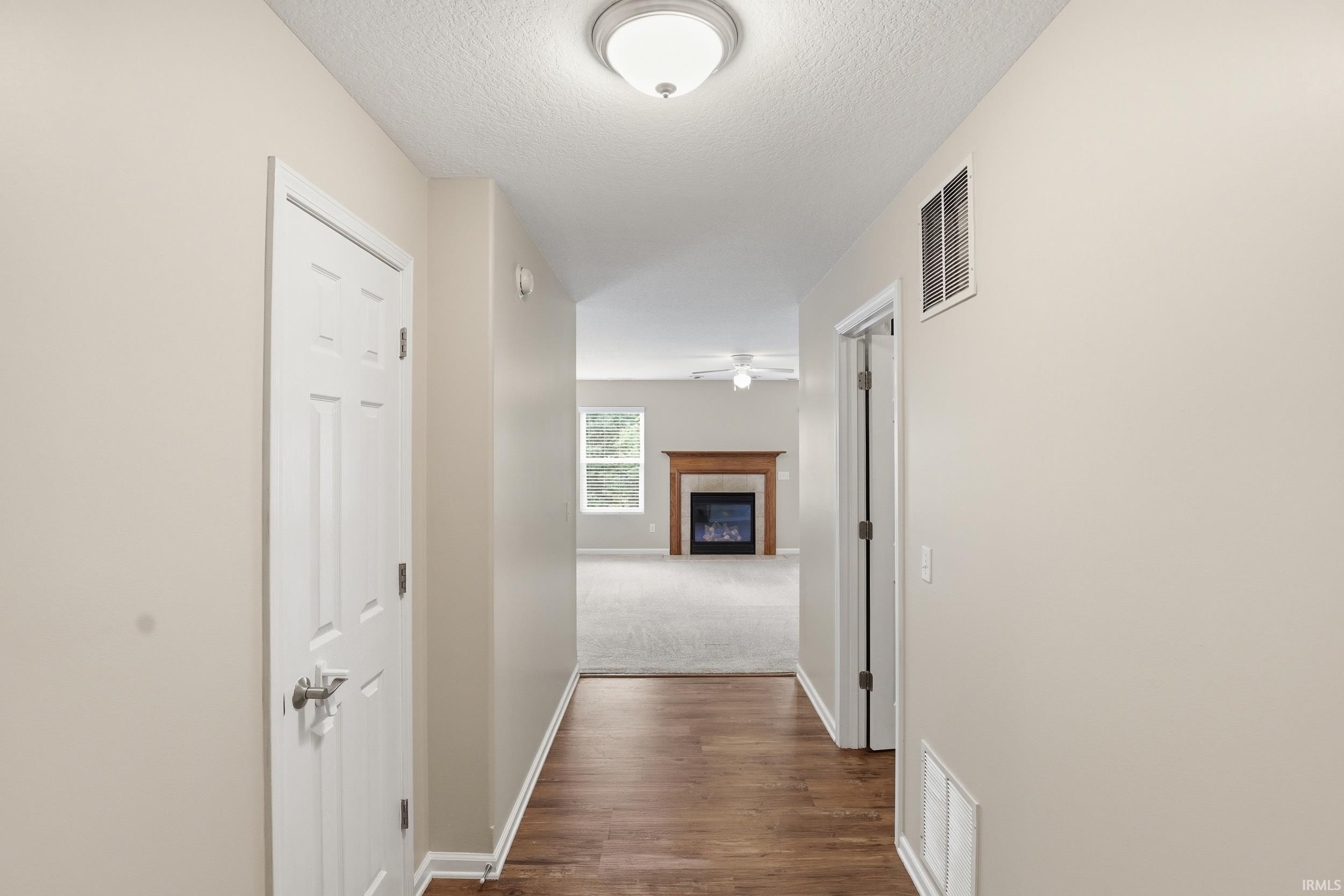 Hallway featuring wood-finish flooring, light neutral paint, and white trim