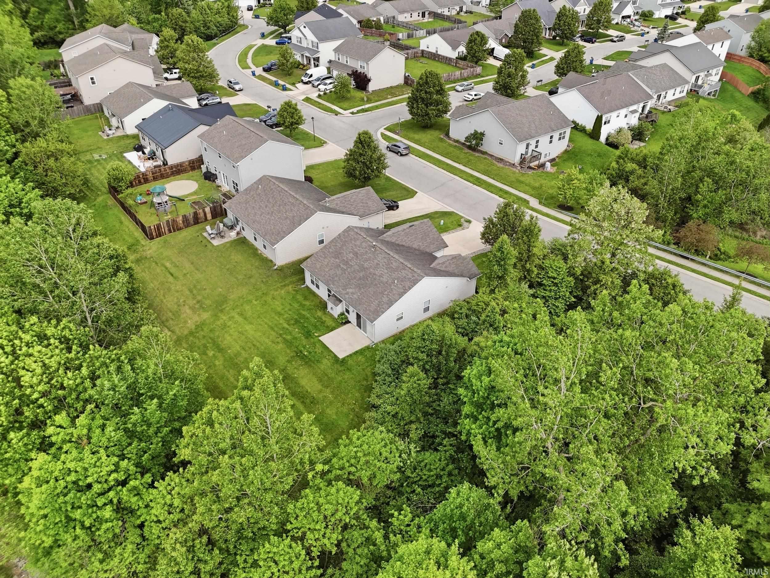 Residential property featuring a spacious grassed yard, mature perimeter trees, and a concrete patio