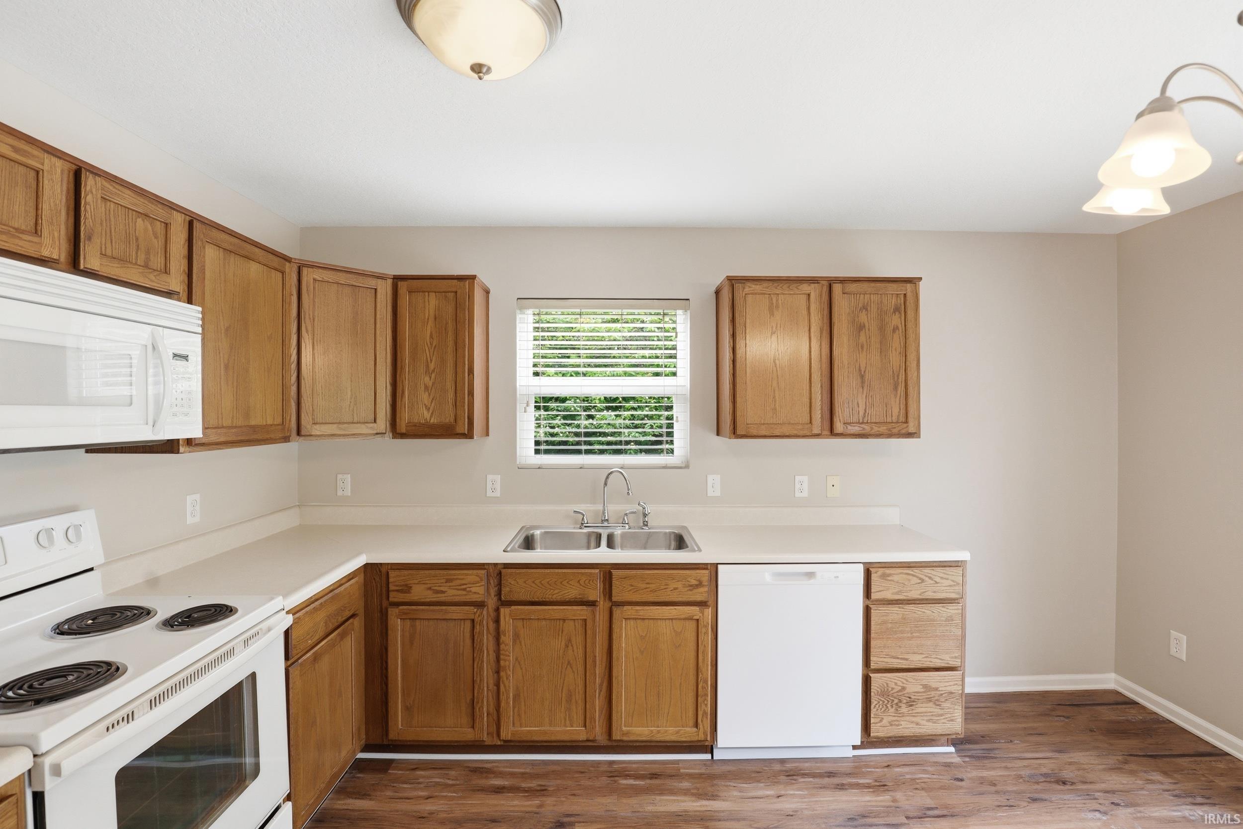 Kitchen featuring wood-finish cabinetry, white countertops, and wood-finish flooring