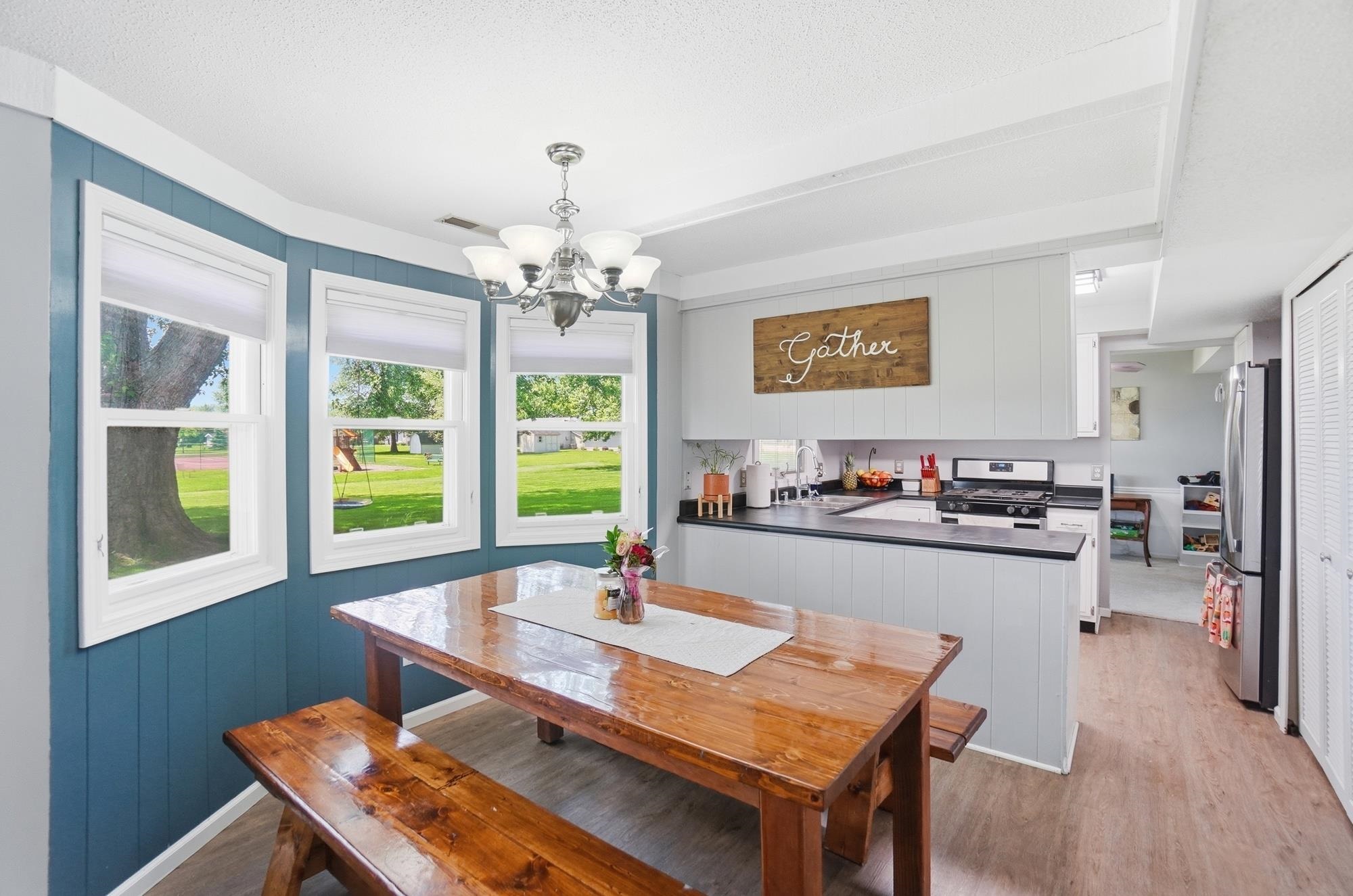 Open-concept living space featuring a bay window, wood-finish flooring, recessed lighting, and a kitchen with built-in cabinetry and stainless steel appliances