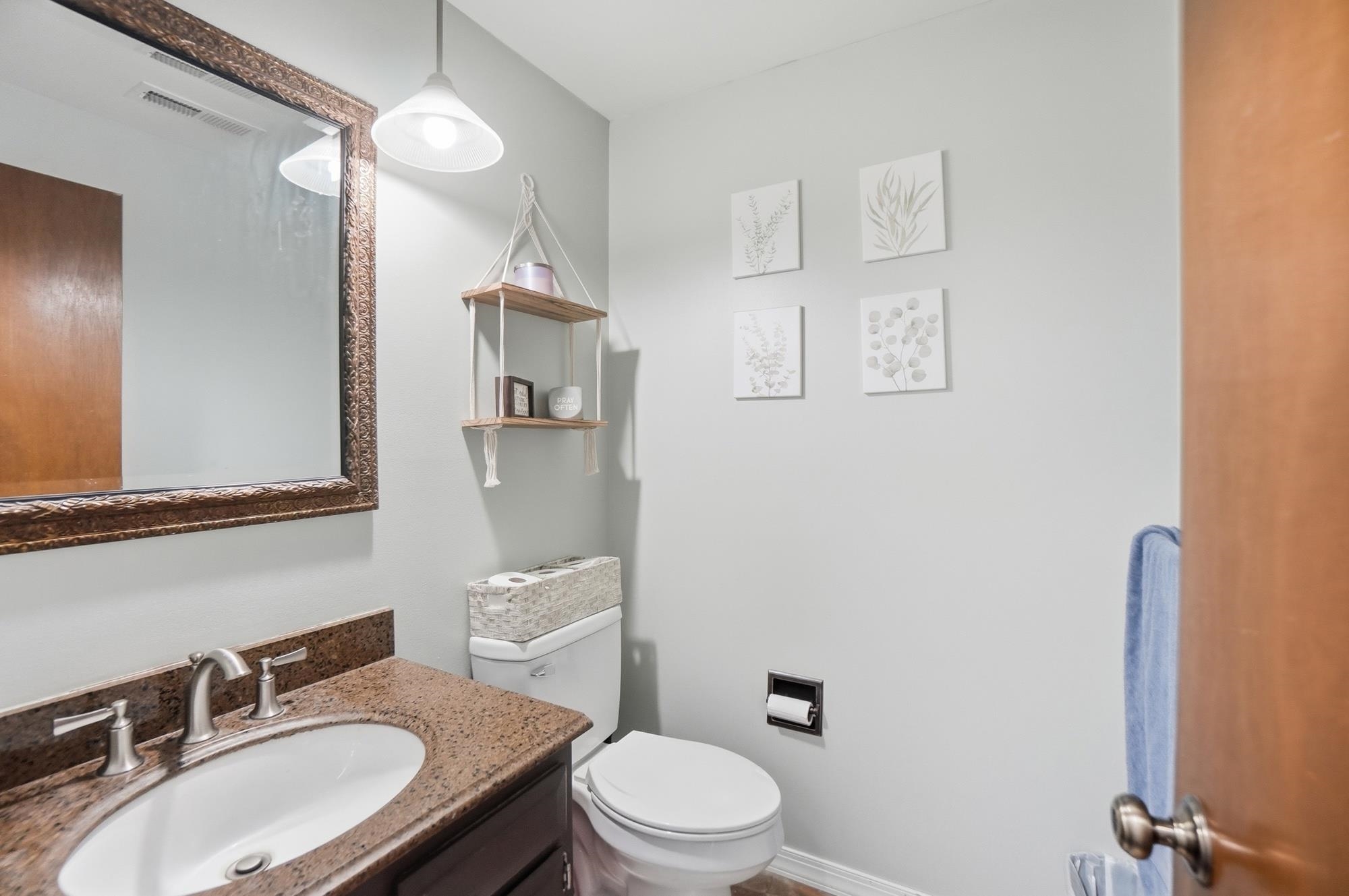 Bathroom featuring a vanity with an undermount sink, granite-style countertop, and dark wood-finish cabinetry