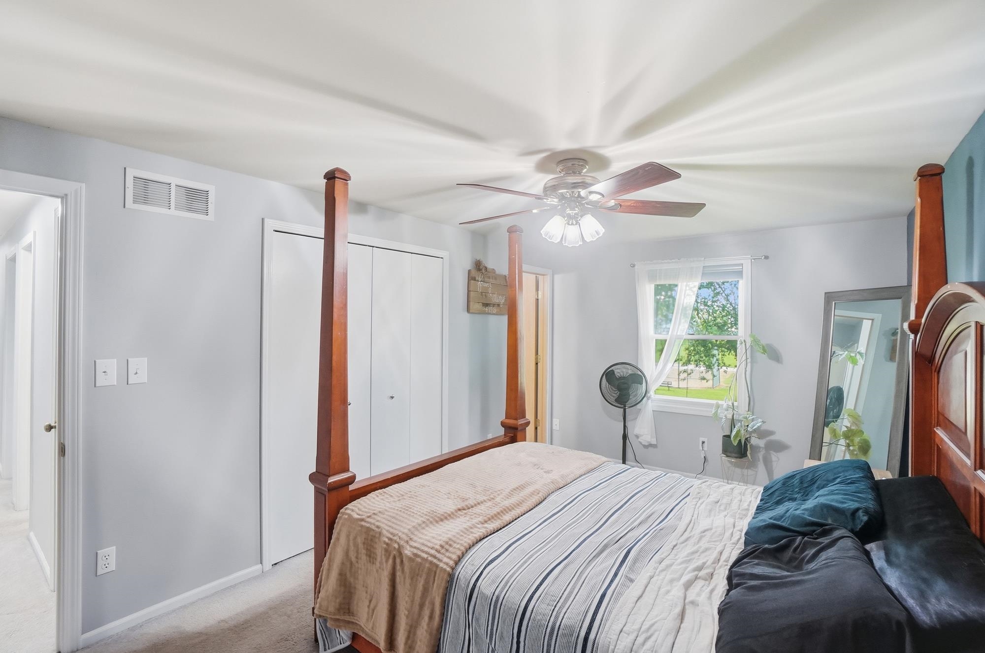 Room featuring a ceiling fan with light fixture, window with exterior landscape, and a bi-fold closet