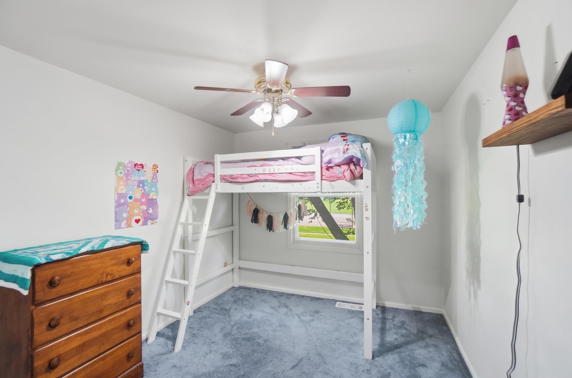 Bedroom featuring a single window, light blue carpeting, and a ceiling fan with integrated lighting